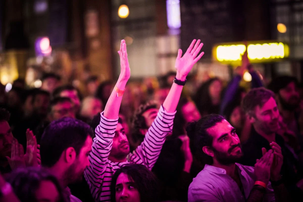 Crowd at a concert with people clapping and raising hands