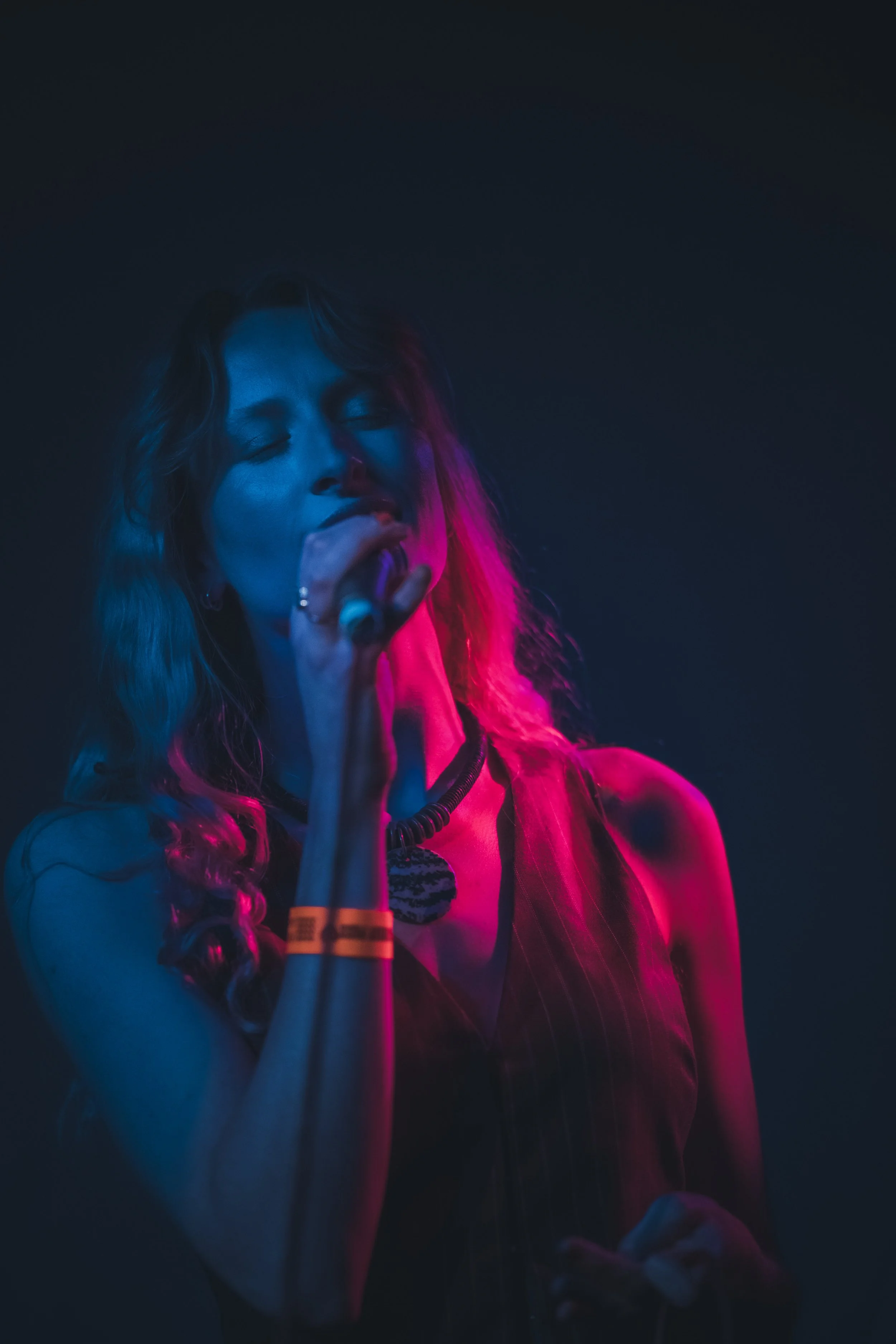 Person singing on stage with colorful lighting