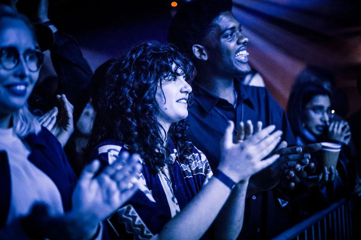 Audience clapping at a concert in blue lighting