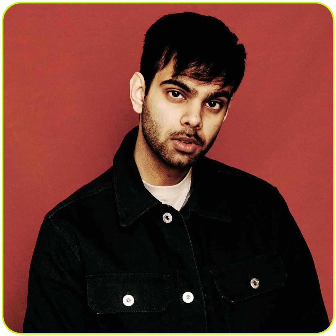 Portrait of a young man with dark hair and a beard wearing a black jacket against a red background