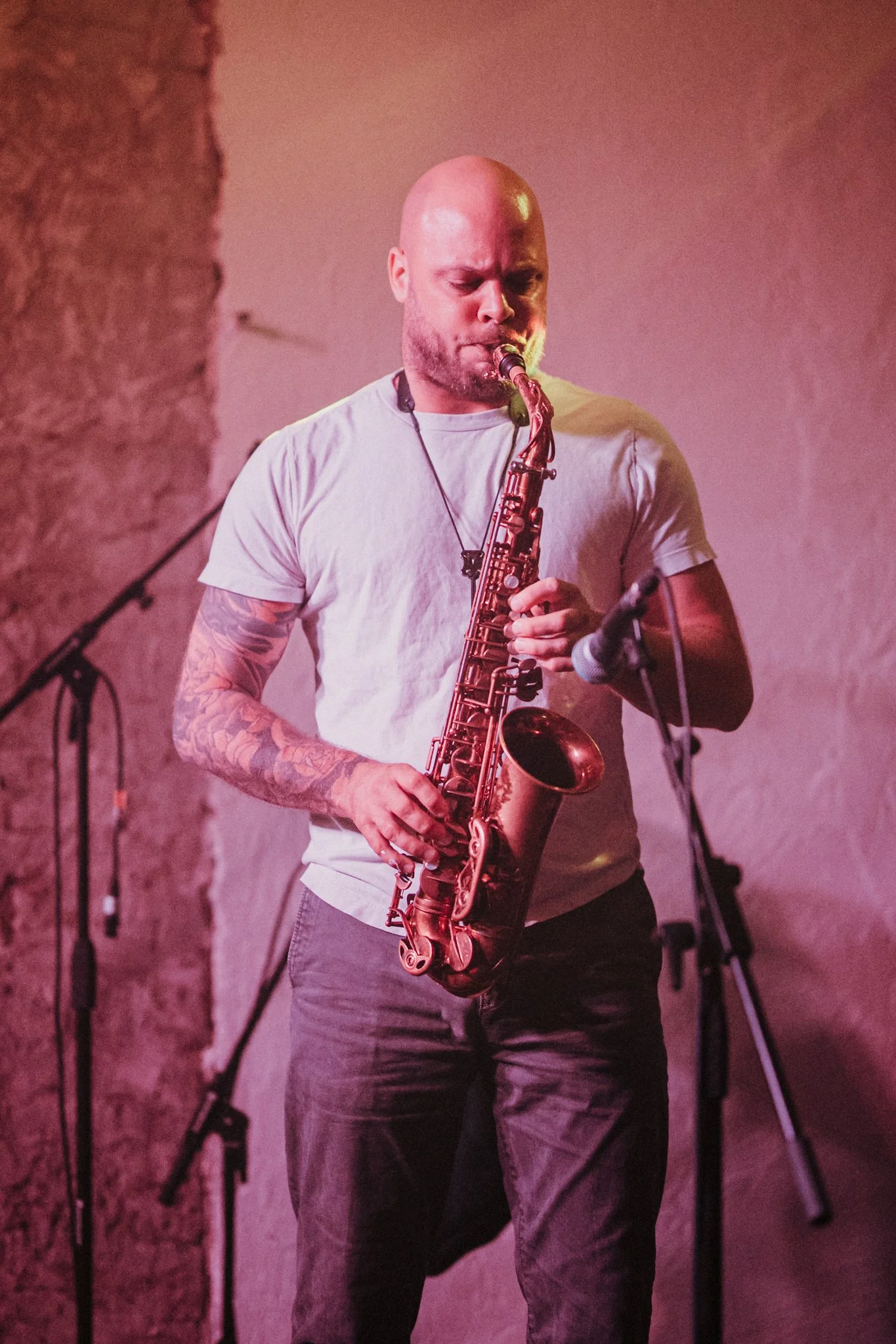 Man playing a saxophone on stage with a microphone nearby.