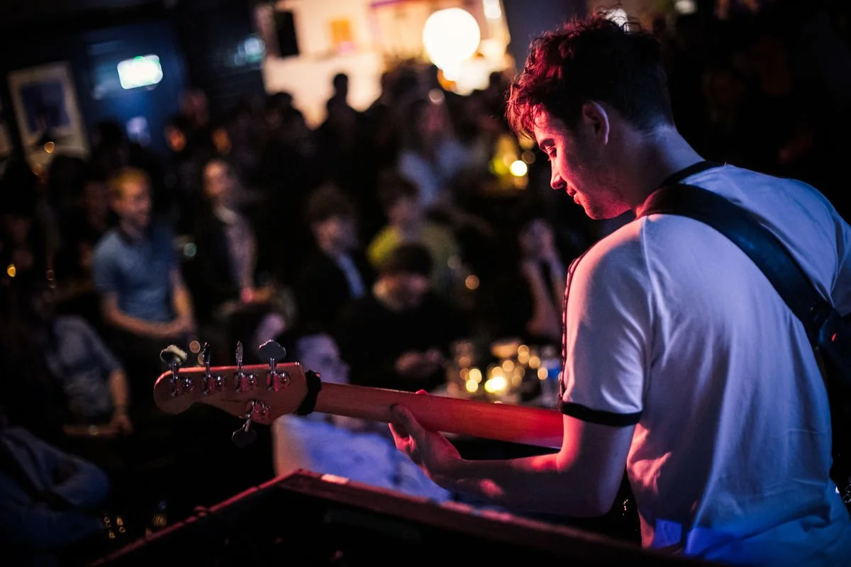 Musician playing guitar on stage with audience in background
