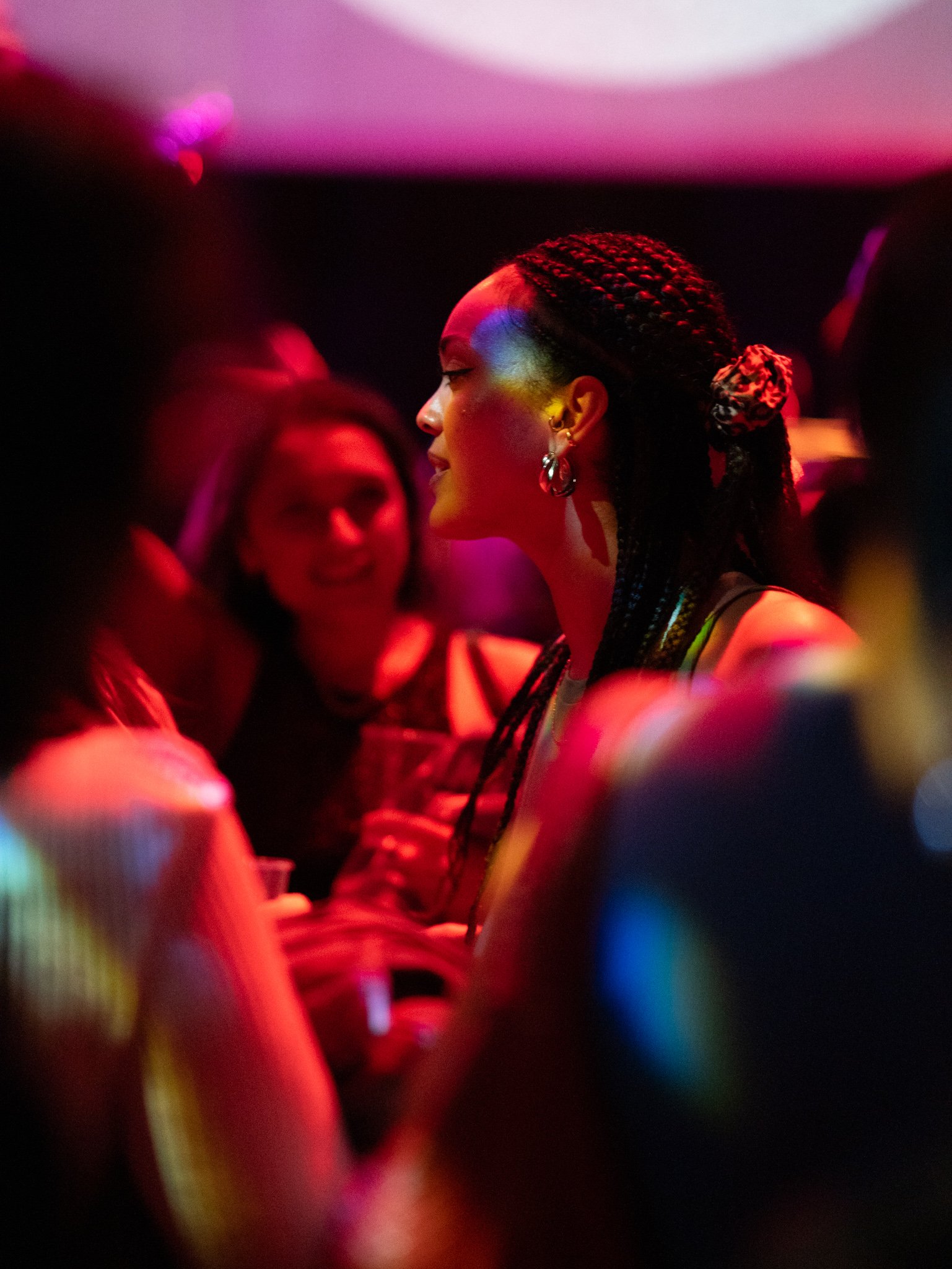 People socializing in a dim, colorful club environment.