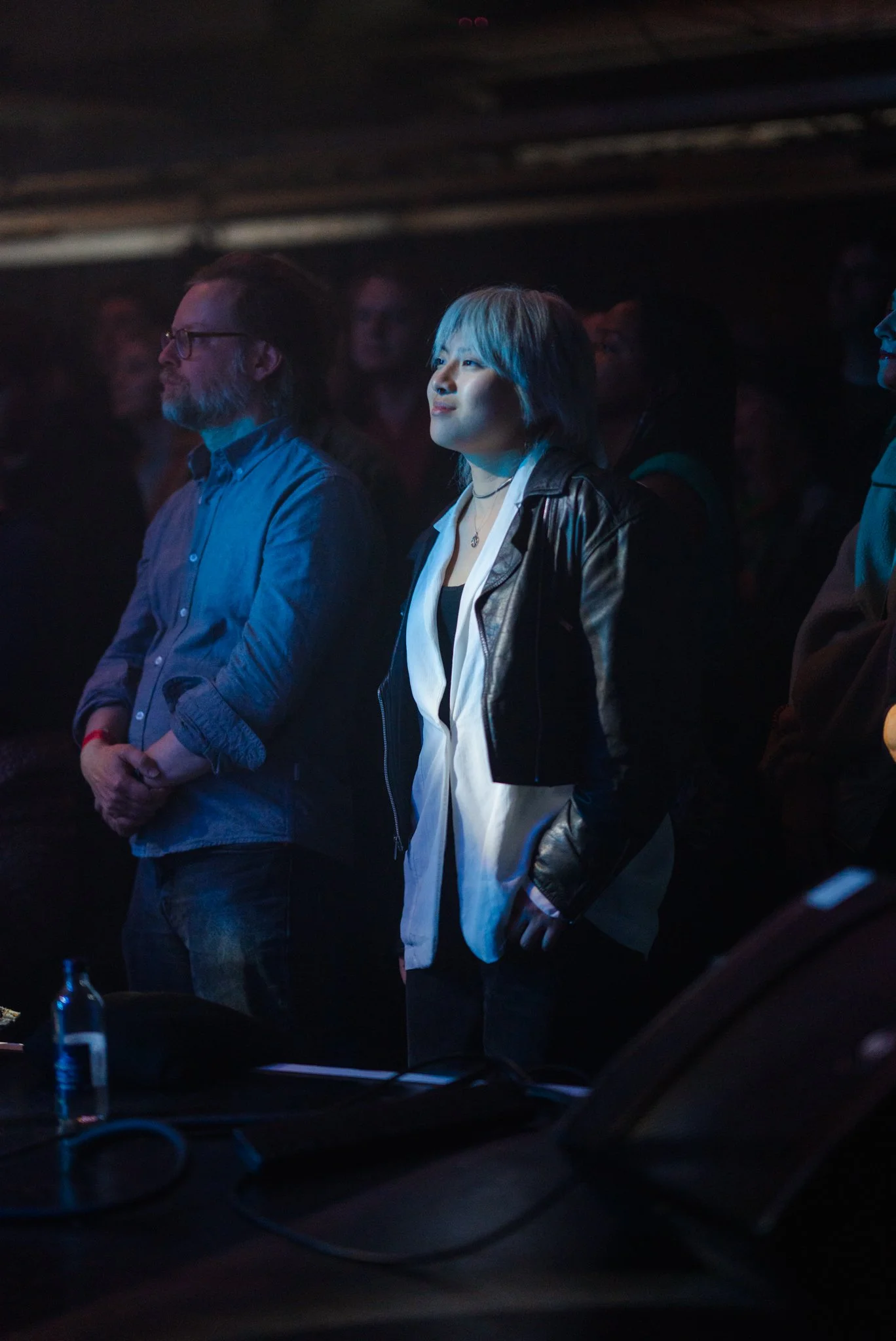 People attentively watching a performance in a dimly lit venue.