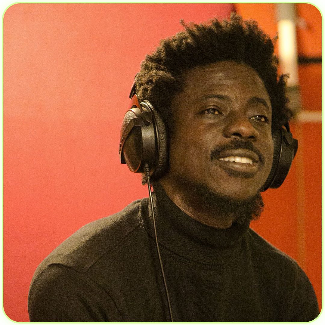 A young man wearing headphones and smiling, with a red background.