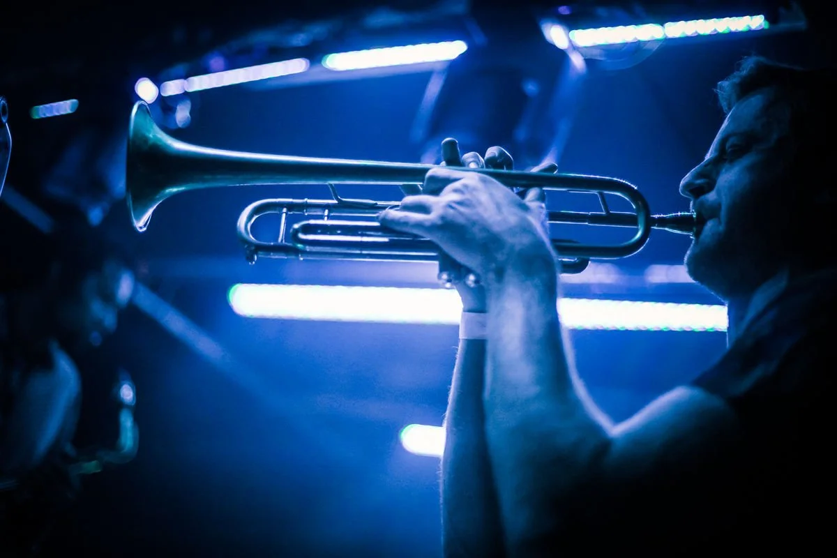 Musician playing trumpet with blue stage lights