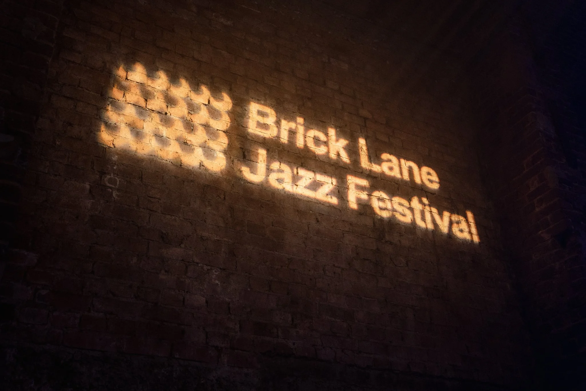 "Brick Lane Jazz Festival" projected on a brick wall.