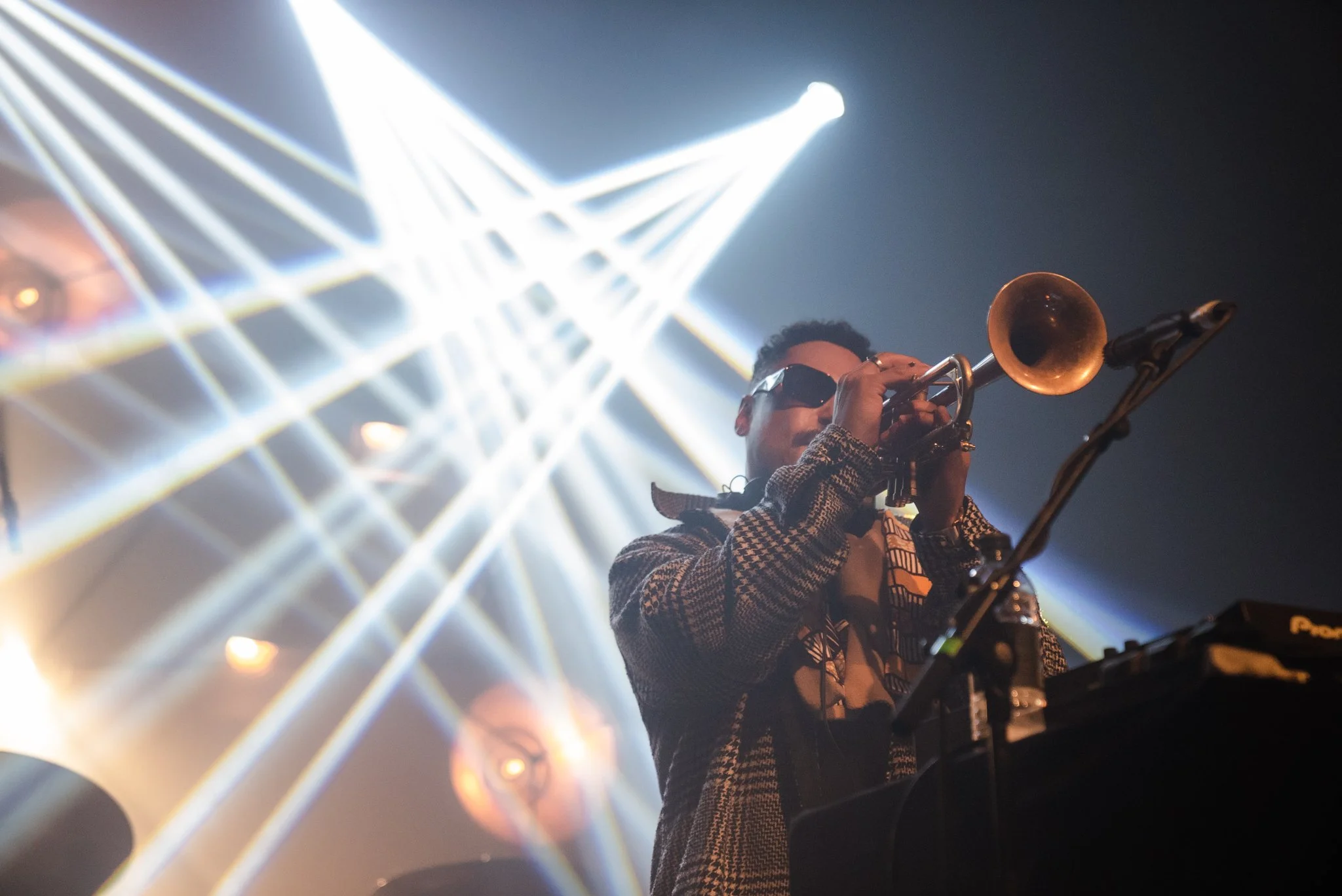 Musician playing trumpet on stage with dramatic lighting.