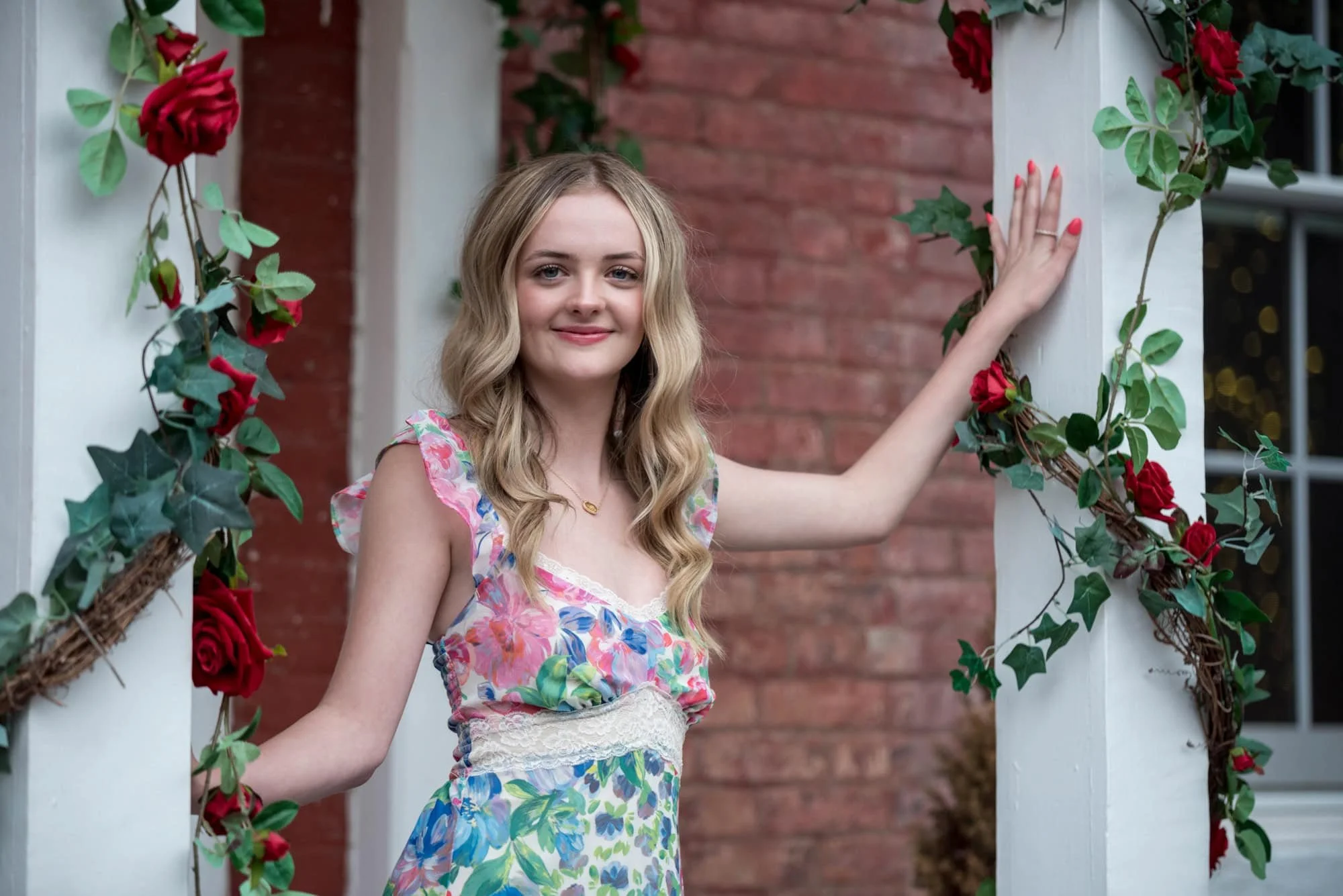 A spring picture captures a high school senior girl wearing a floral long dress next to blooming flowers in historic St. Charles.