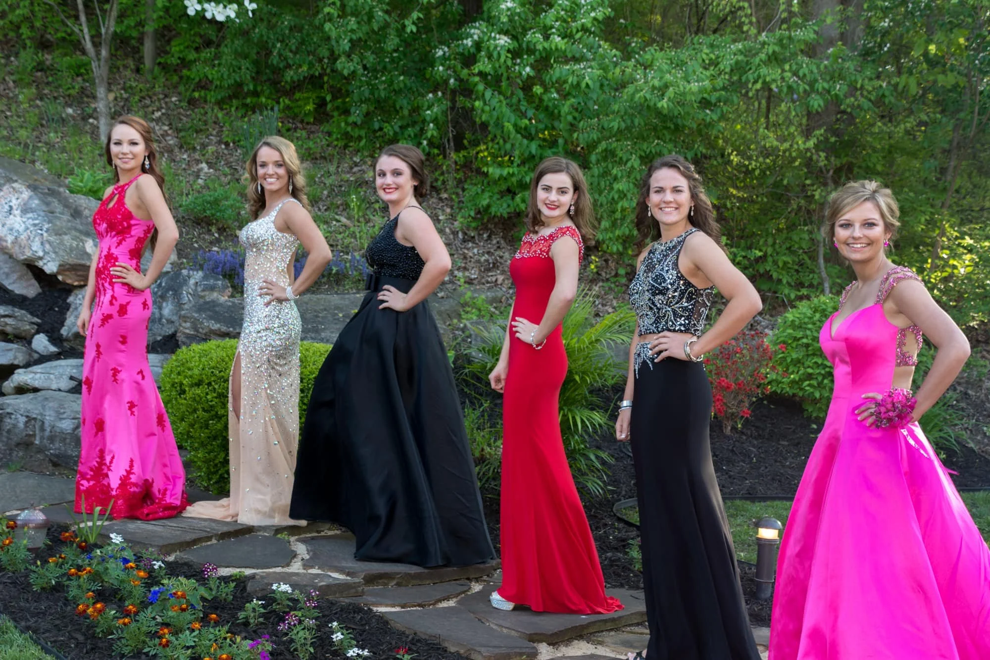 Group of six senior girls standing on a rocky pathway in front of the woods wearing colorful dresses for their prom photos in Columbia IL.