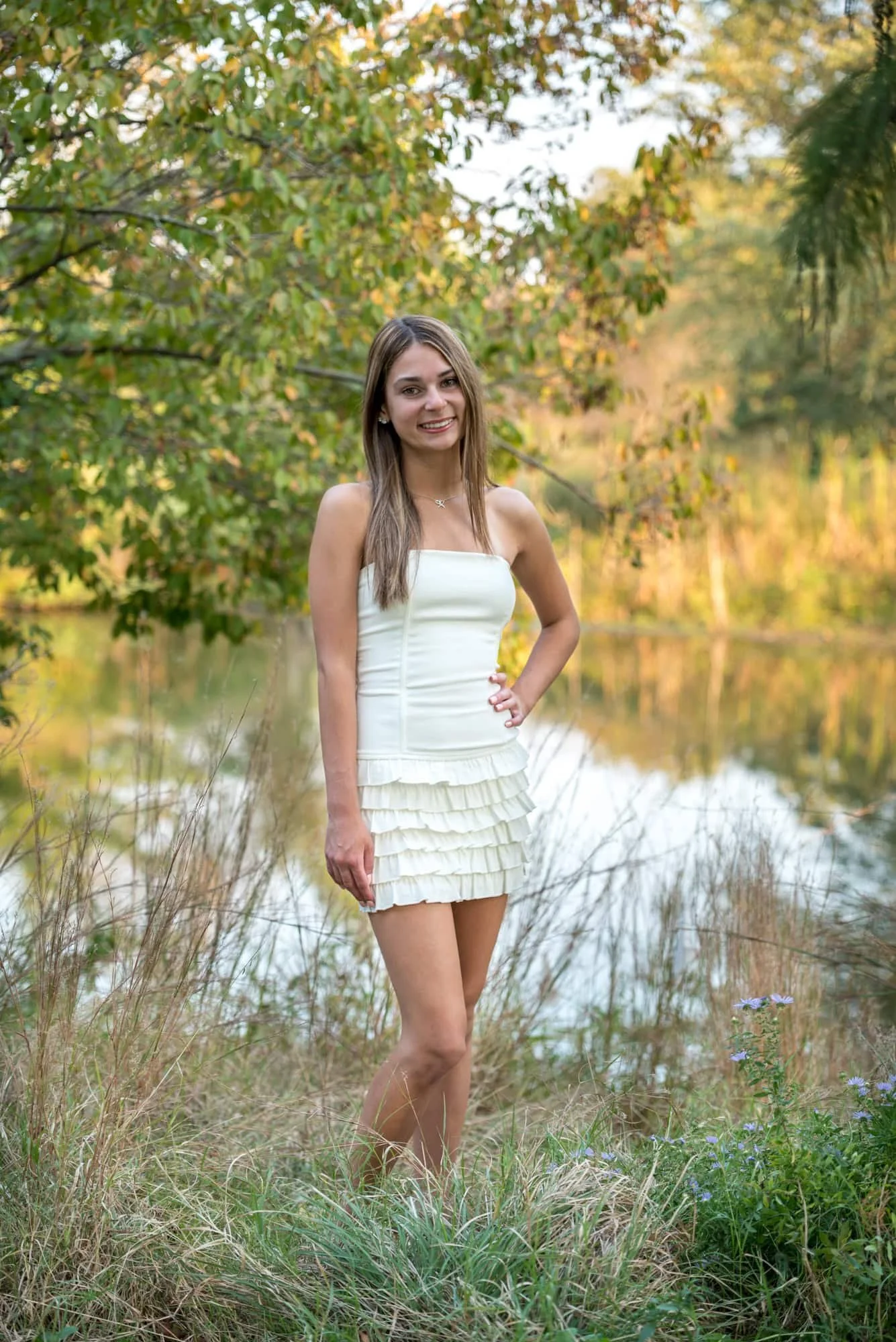 Autumn style senior photo capturing a girl in a white dress as the fall sunset illuminates the changing leaves in St. Louis.