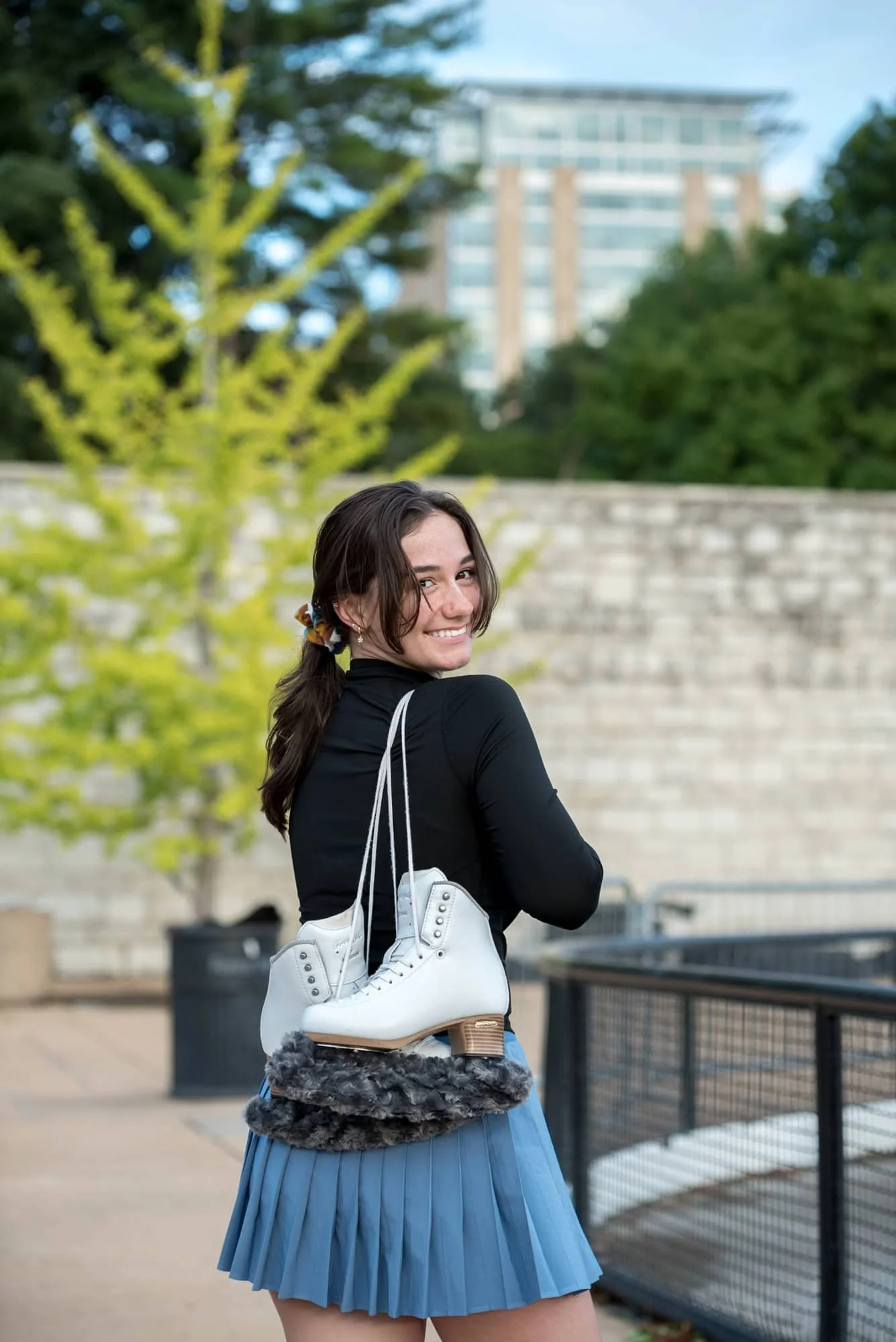 Looking back over her shoulder with her ice skates slung over her back, a senior girl poses for a photo in St. Louis County.