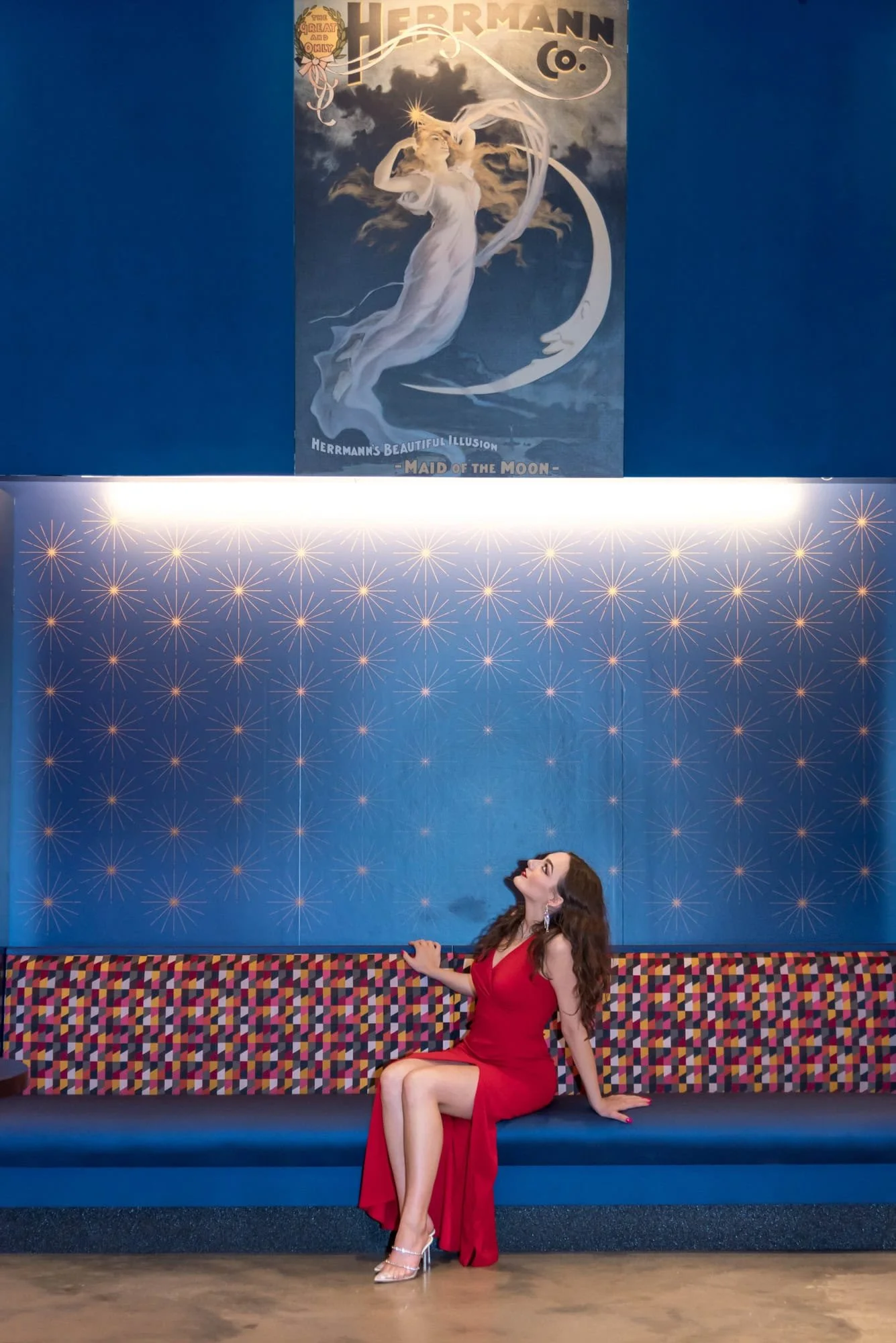 A photo shows a high school senior girl wearing a formal red dress inside a business by a St. Louis photographer.