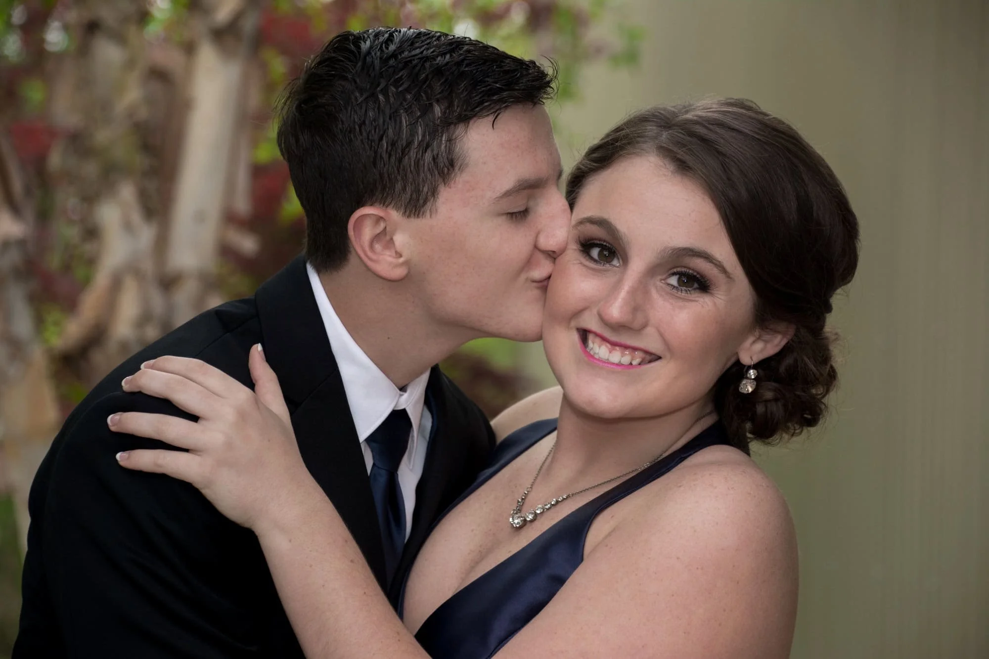 Sweet close-up picture of a boy kissing his date on the cheek as she smiles for the camera before their Columbia Illinois prom dance.