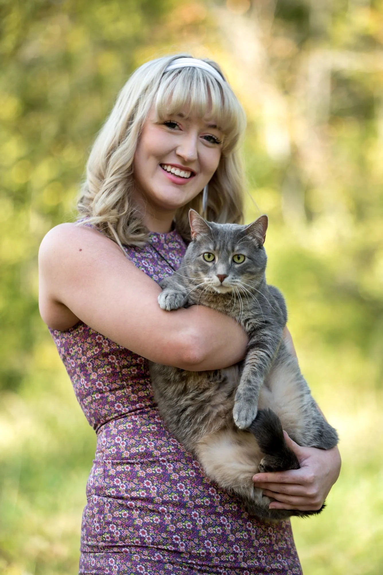 During a fall photo session in Monroe County, a senior girl in a purple dress holds a cat.