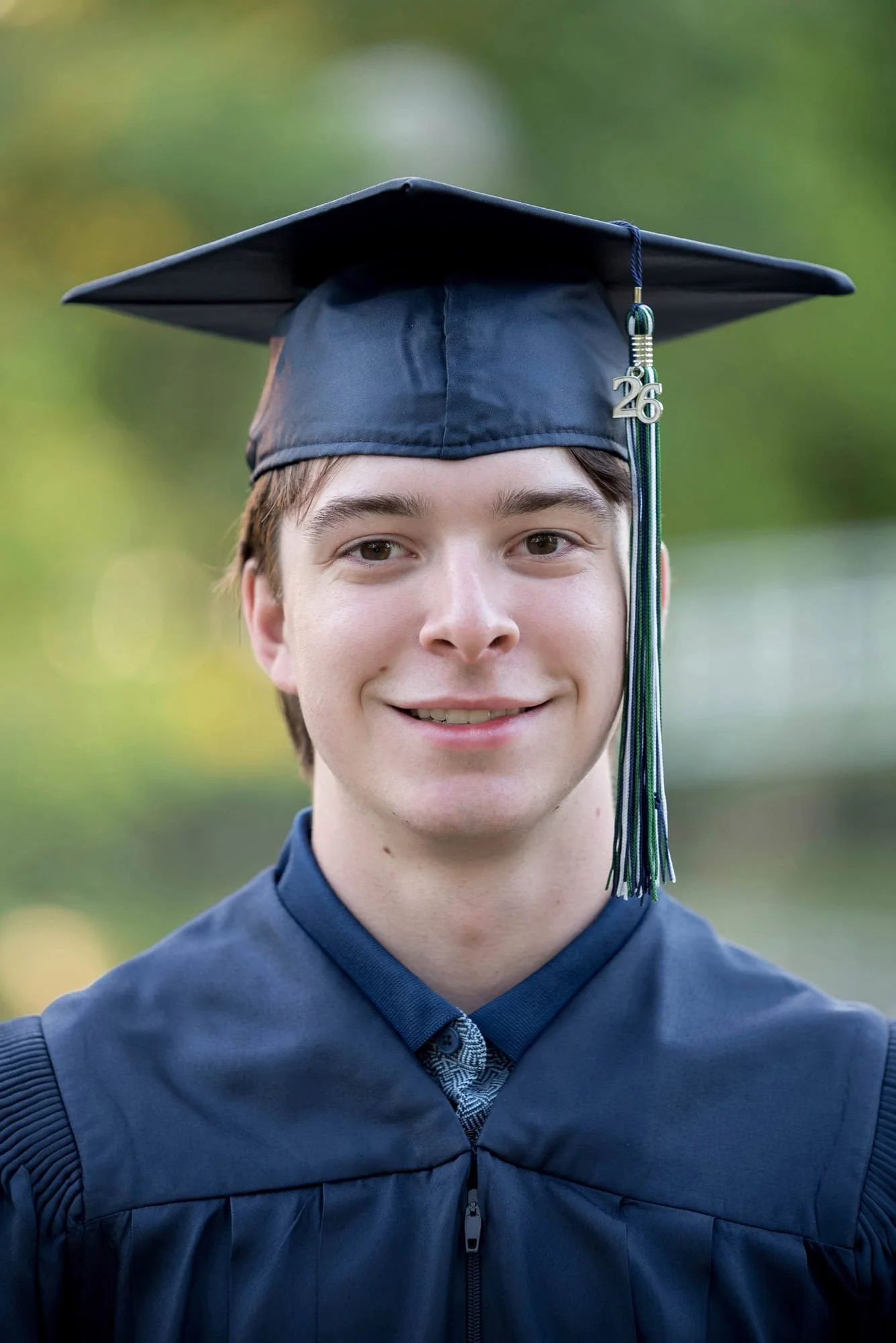 Close-up picture of a senior boy in a navy blue graduation cap and gown with a "26" tassel taken by St. Louis senior photographer.