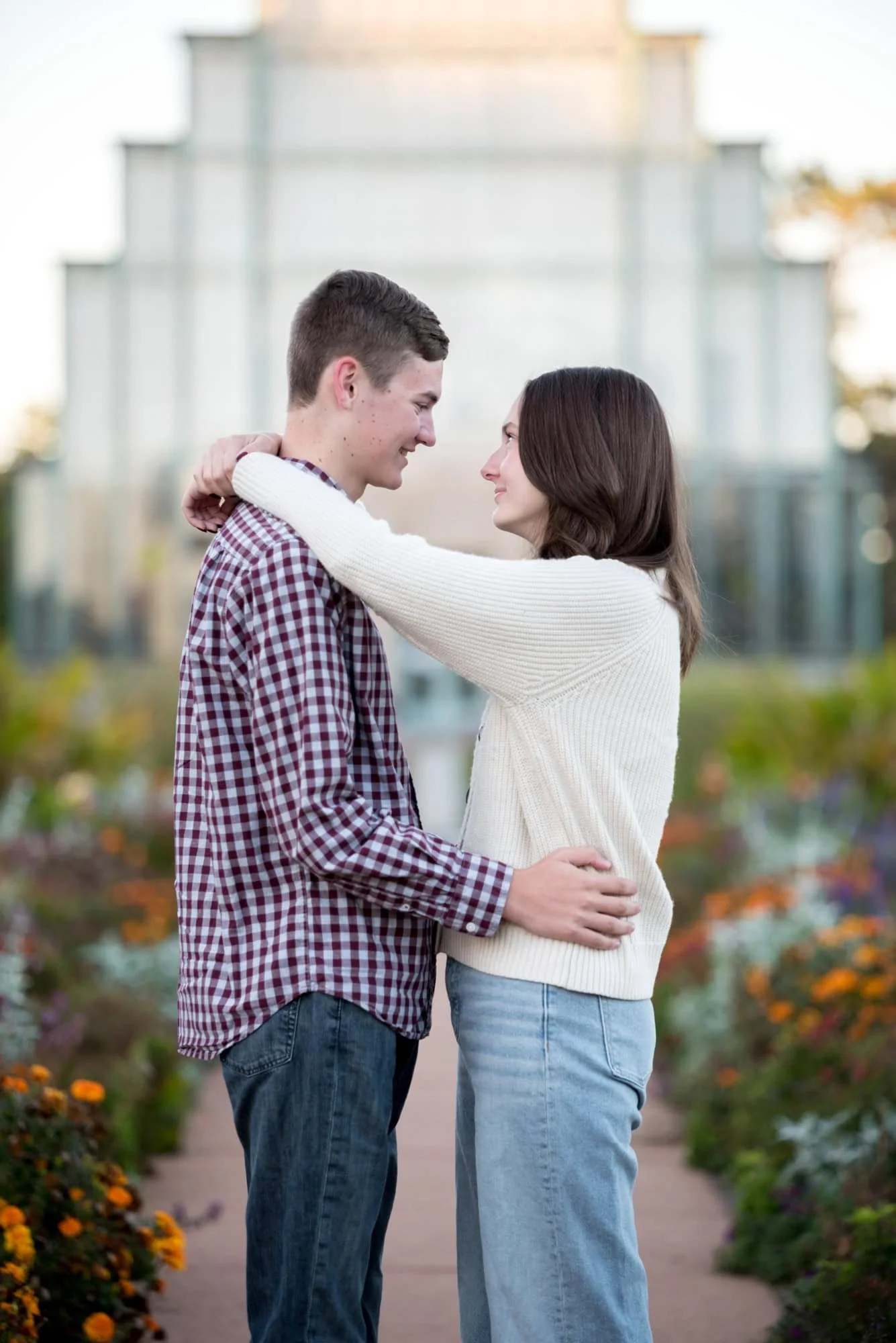 With their arms around each other, a senior girl and her boyfriend smile during a whimsical outdoor photo session at Forest Park.