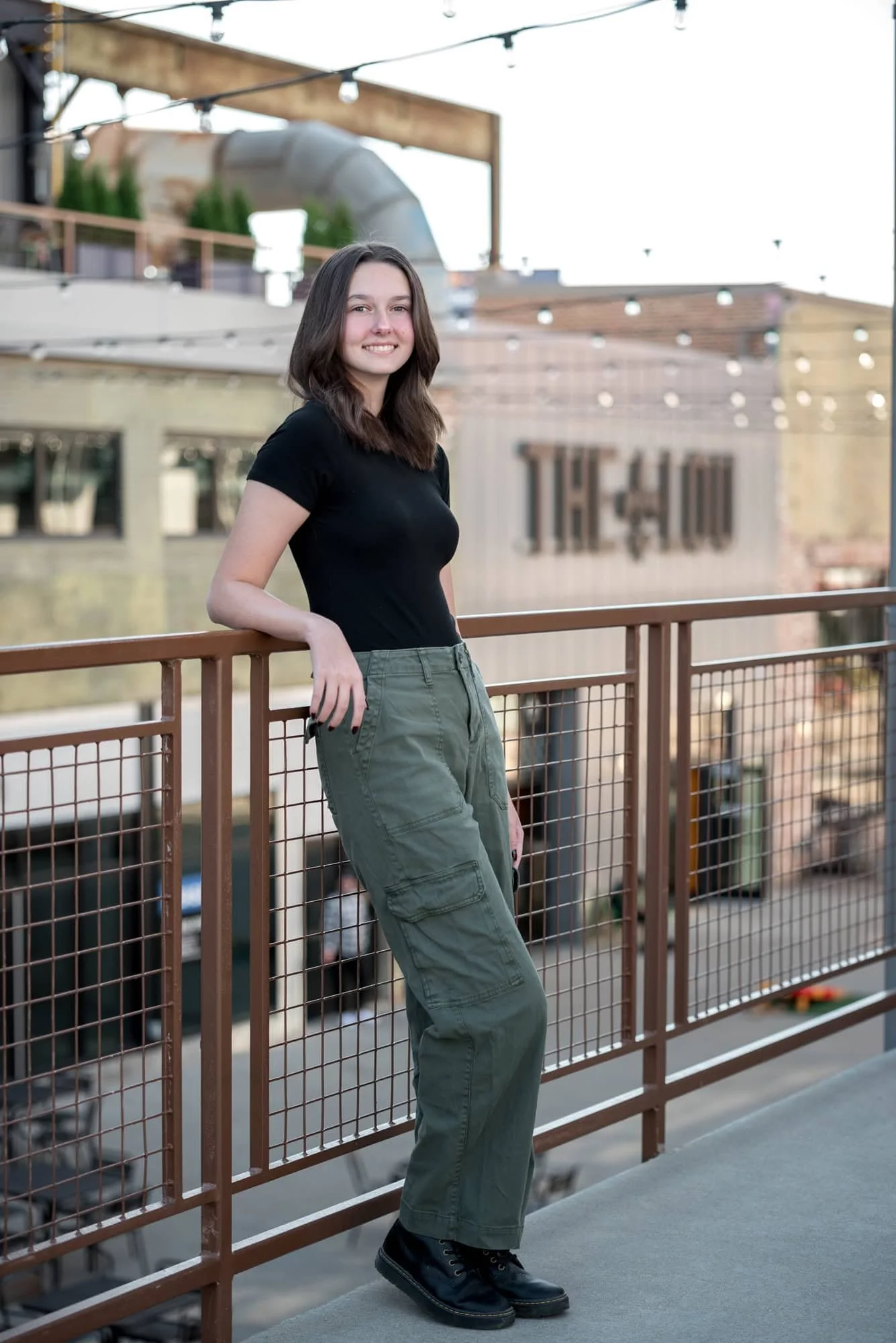 A St. Louis senior girl leans against a black metal fence for an urban picture with outdoor architectural elements.