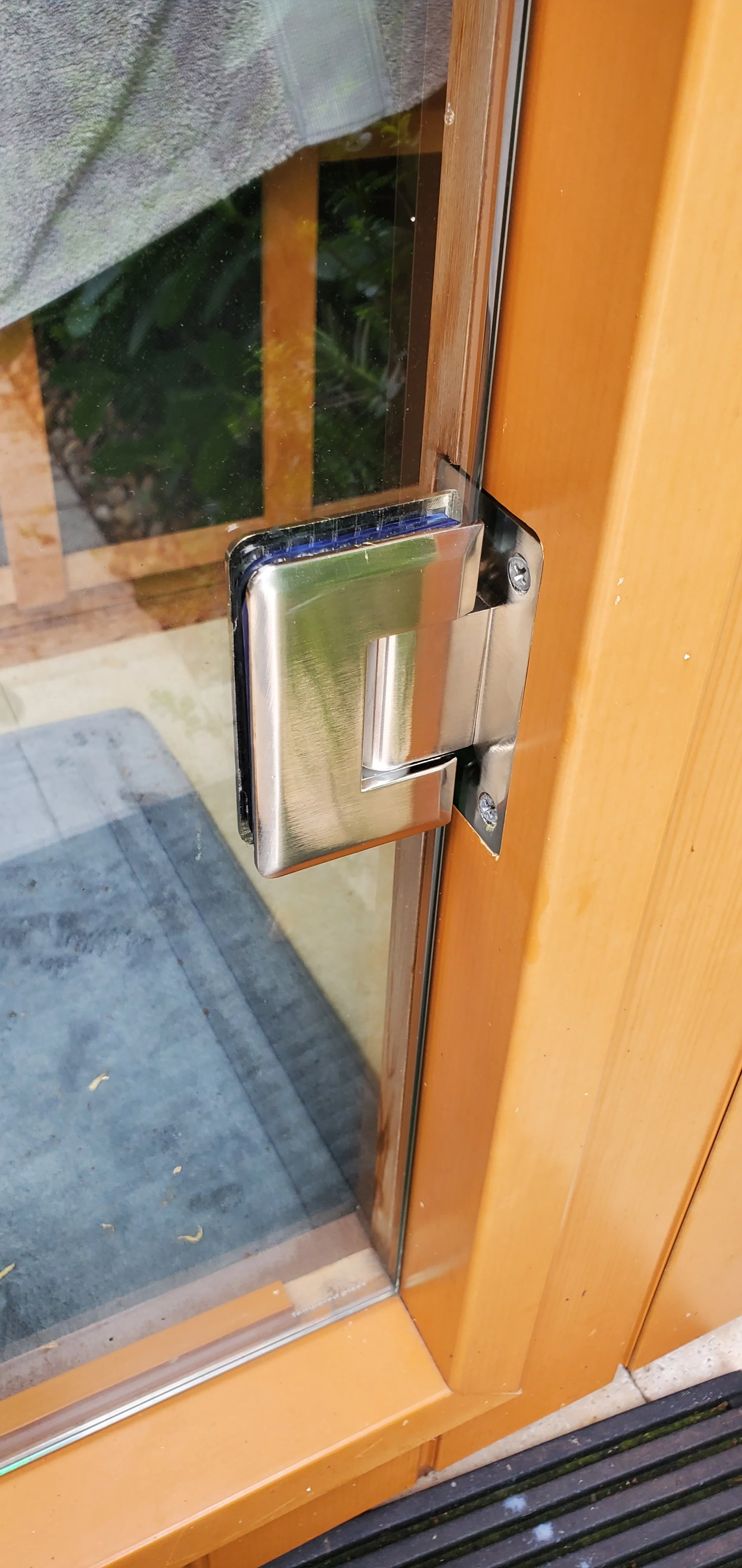 Installation Service  in Broward County ,West Palm Beach, Boca Raton, Delray Beach, Boynton Beach,   Close-up of a wooden door with a modern silver door handle and lock, glass panels, and a view of the outside ground.