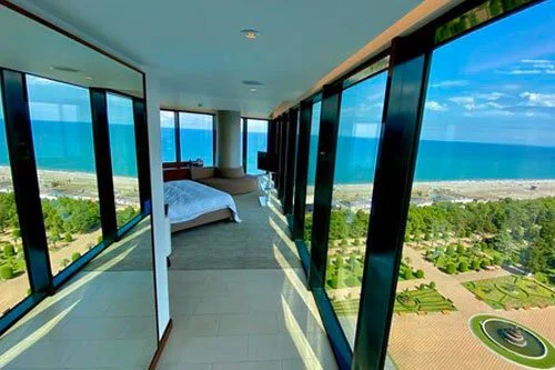 commercial cleaning service, Modern bedroom with floor-to-ceiling windows overlooking the ocean, featuring a bed and seating area.