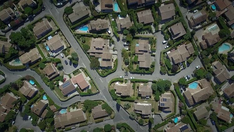 Moving Service, and Cleaning Service, An aerial view of a suburban neighborhood with houses, streets, driveways, trees, and several swimming pools in backyards.