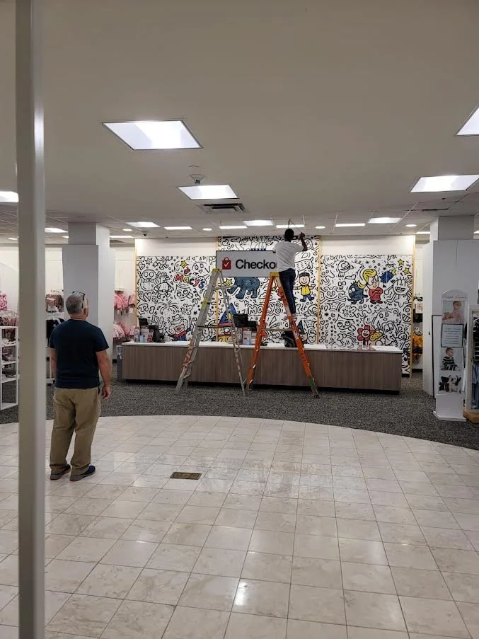 kpg cleaning care and moving service out of state, Two workers on ladders decorating a black and white wall mural in a store with the 'Checker' sign above the counter and a man observing.