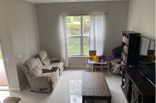Residential professional cleaning Living room with beige sofa, large window with curtains, black entertainment center, and a wooden coffee table.