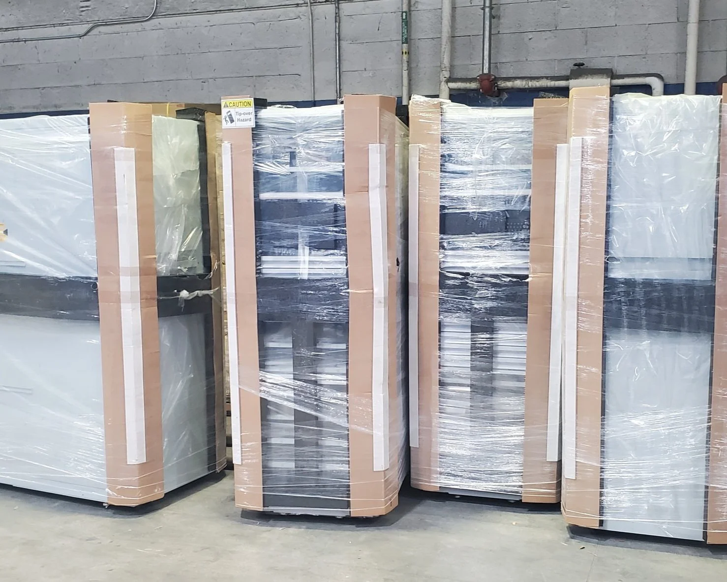professional unloading and load service, Several refrigerators wrapped in plastic and cardboard, stored upright in a warehouse.