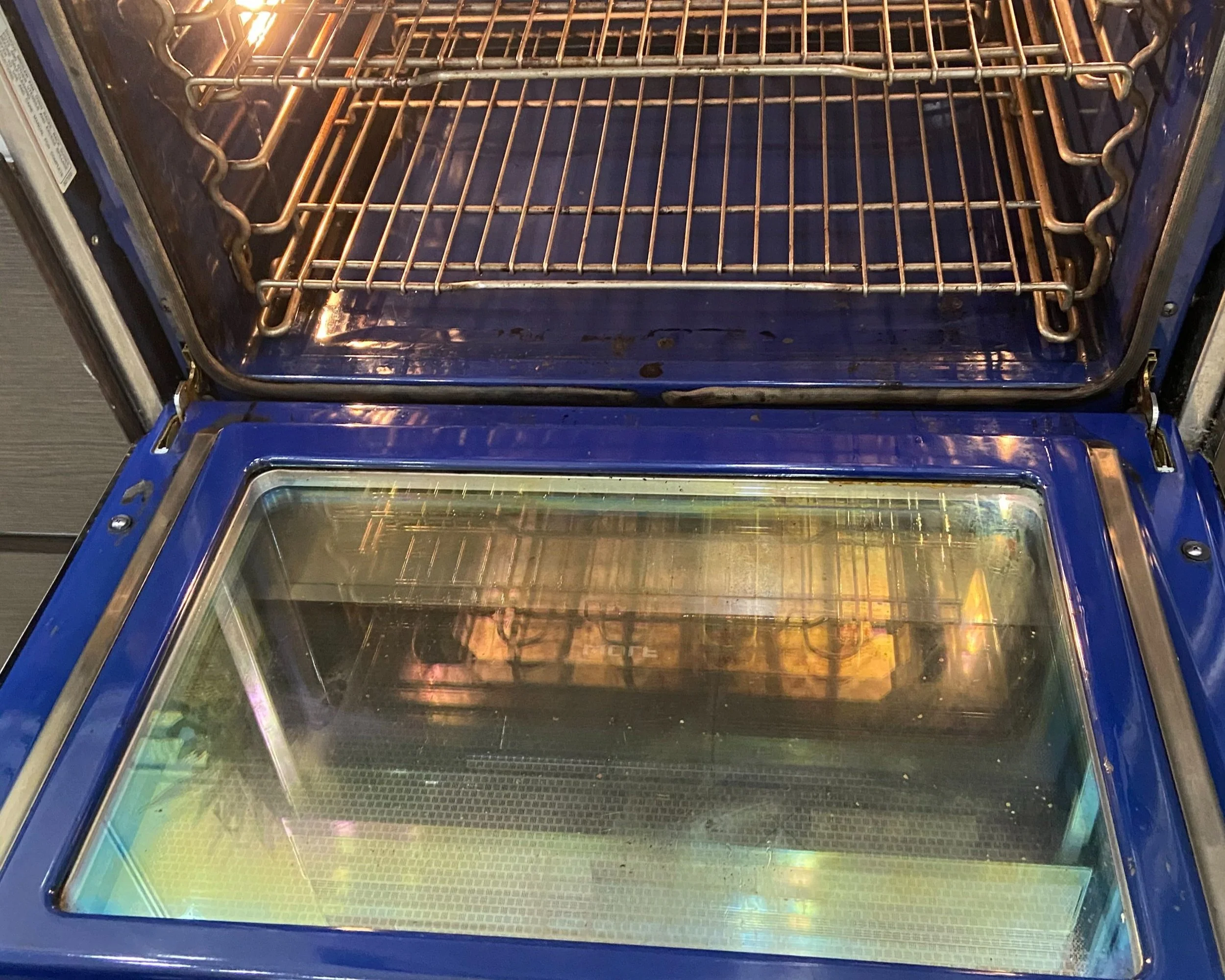 KPG cleaner disinfecting Inside view of an empty oven with two racks, one on top and one on the bottom.