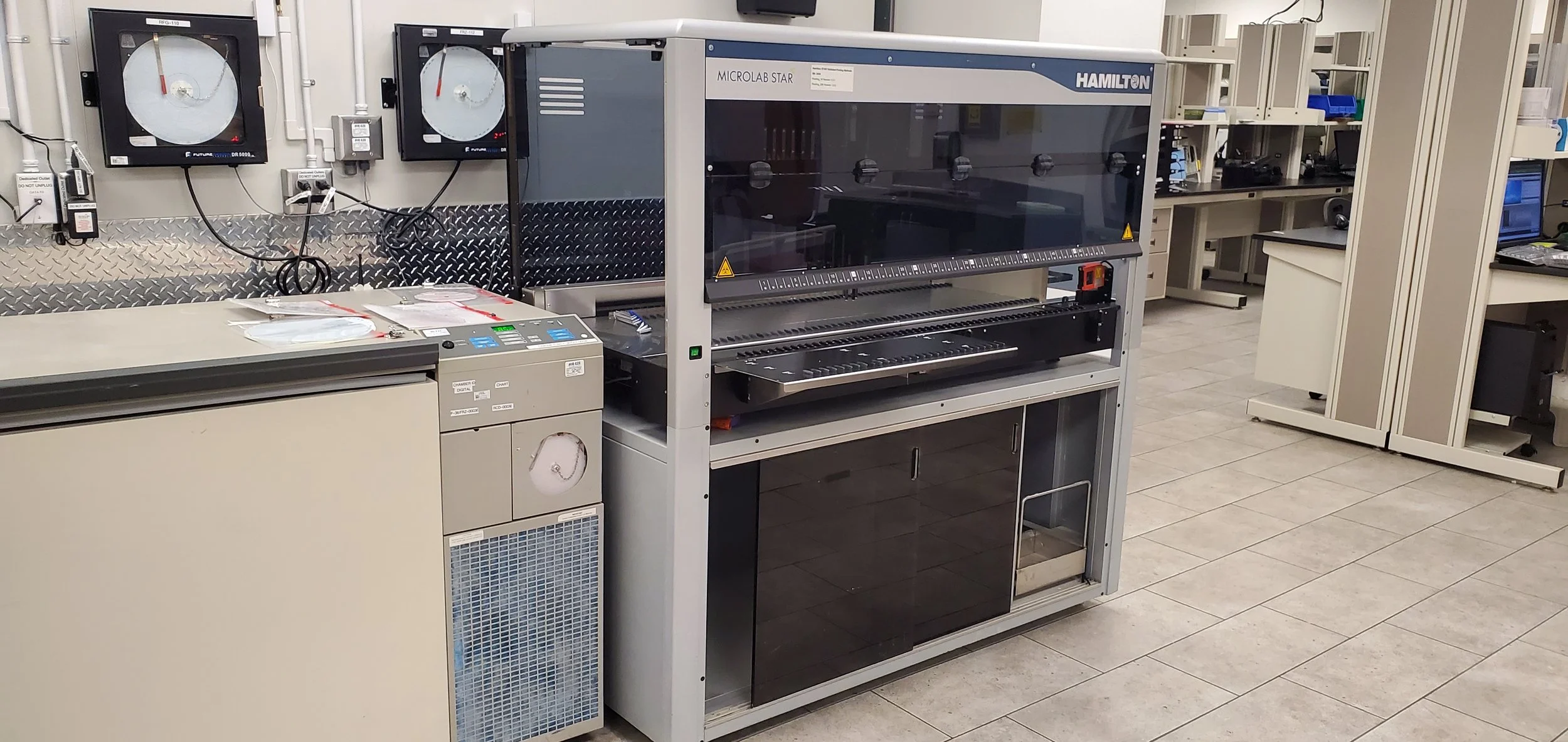 Installation Service Laboratory workspace with scientific equipment including a Hamilton Microlab STAR automated liquid handling system, various monitors, and storage cabinets.
