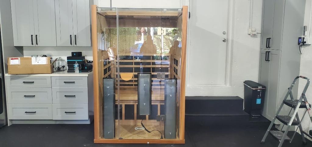 Professional Installation Service in Broward County, An indoor sauna with glass doors and wooden interior, located in a room with gray cabinets, drawers, and a ladder.