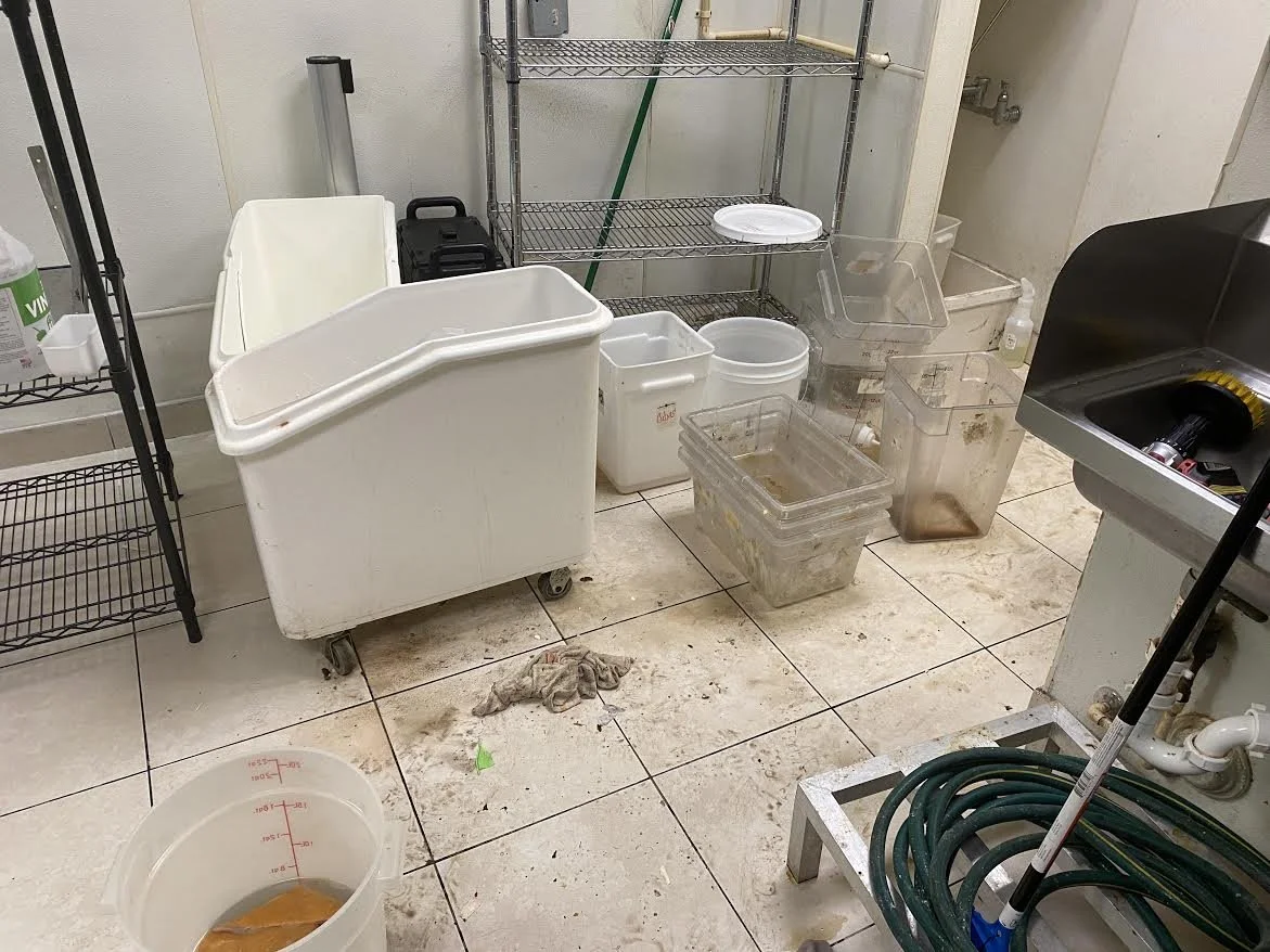 restaurant cleaning service, Cleaning supplies and containers in a commercial kitchen or food preparation area.