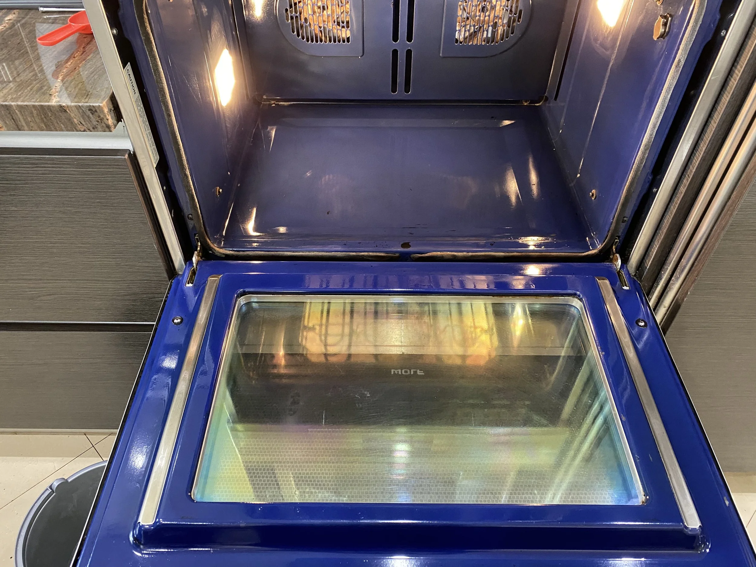 Empty blue display case with glass top and interior lighting, located in a retail setting, possibly for displaying jewelry or small items.