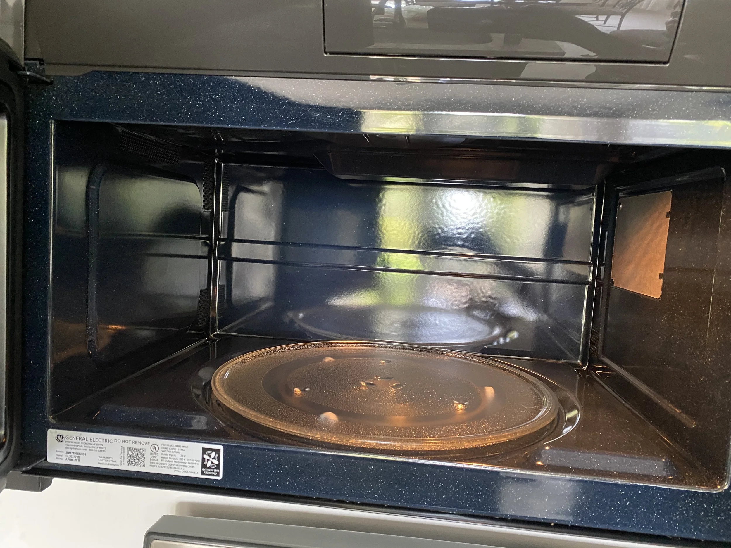 Interior view of an empty, black microwave oven with its door open, showing the turntable and inside space.