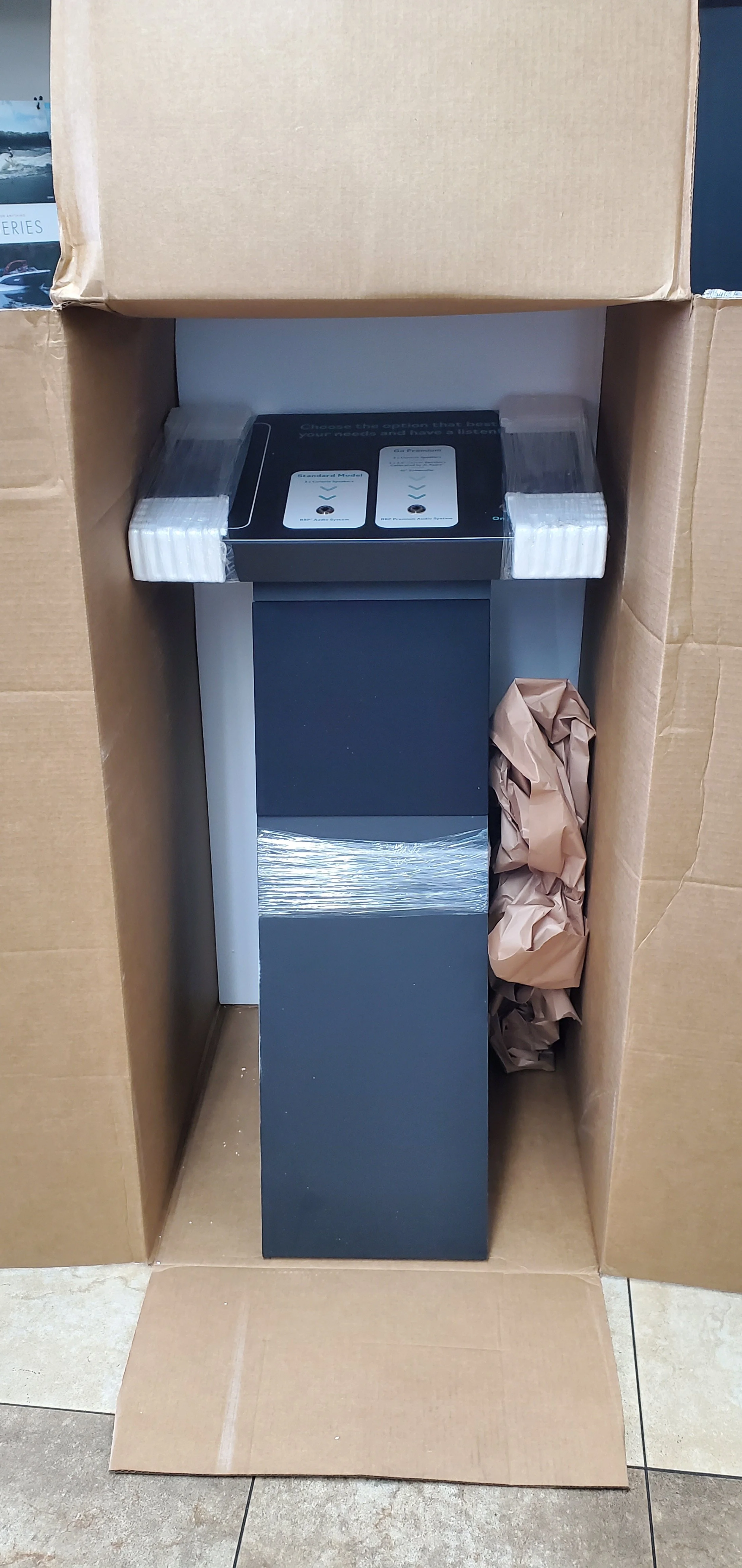 Installation Service Unassembled electronic device in a cardboard box with packing materials, including foam corner protectors, tissue paper, and packaging instructions.