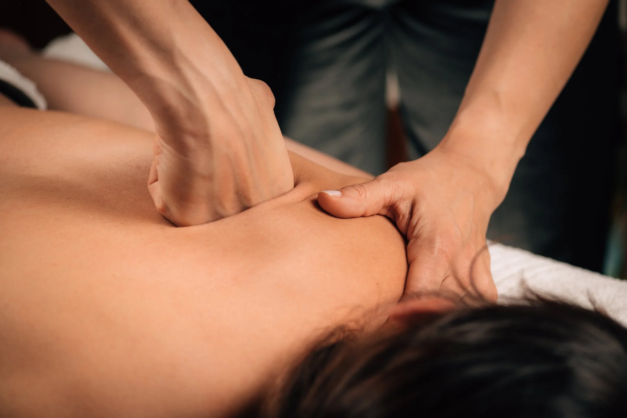 Deep tissue massage applying firm pressure to the upper back to address muscle tension and structural imbalance