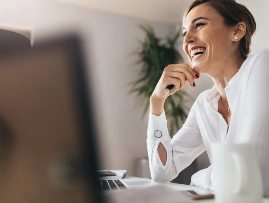 Desk worker sitting comfortably at computer after treatment for desk related neck and shoulder tension