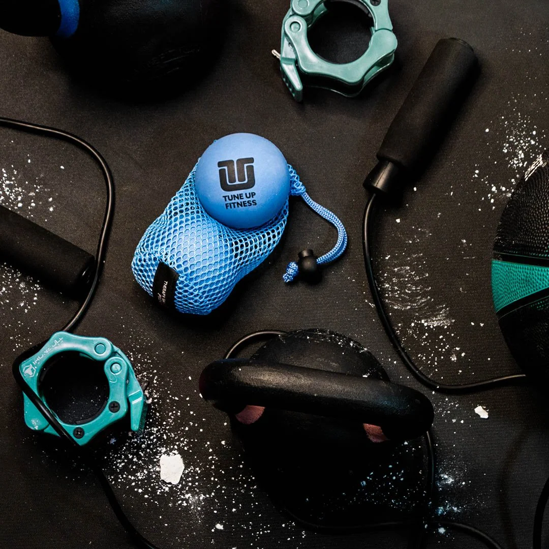 Two blue Tune Up Fitness therapy balls beside a kettlebell and jump rope