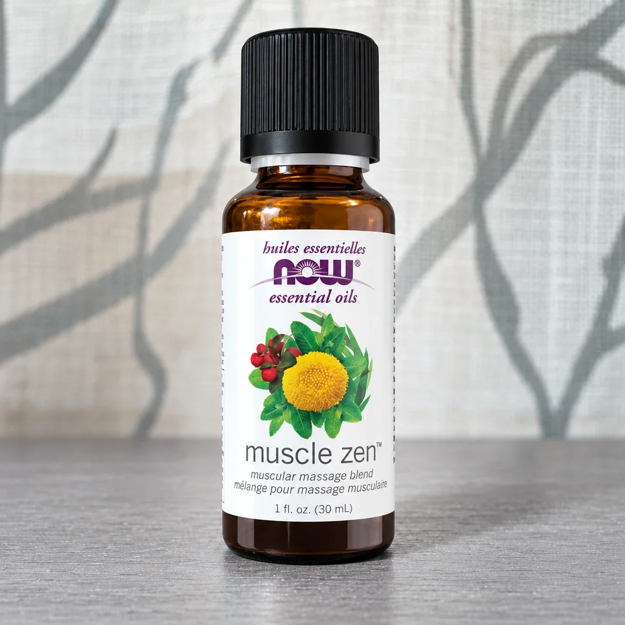 NOW Muscle Zen essential oil blend bottle against a softly lit curtain