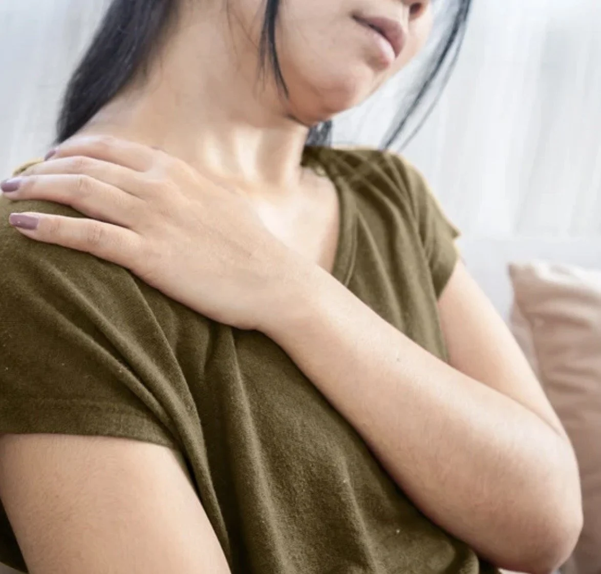 Woman holding shoulder and neck demonstrating muscular tension associated with forward head posture