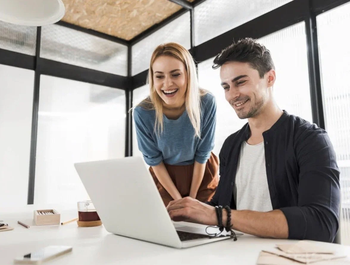 Office workers adjusting computer workstation ergonomics to reduce neck and shoulder strain