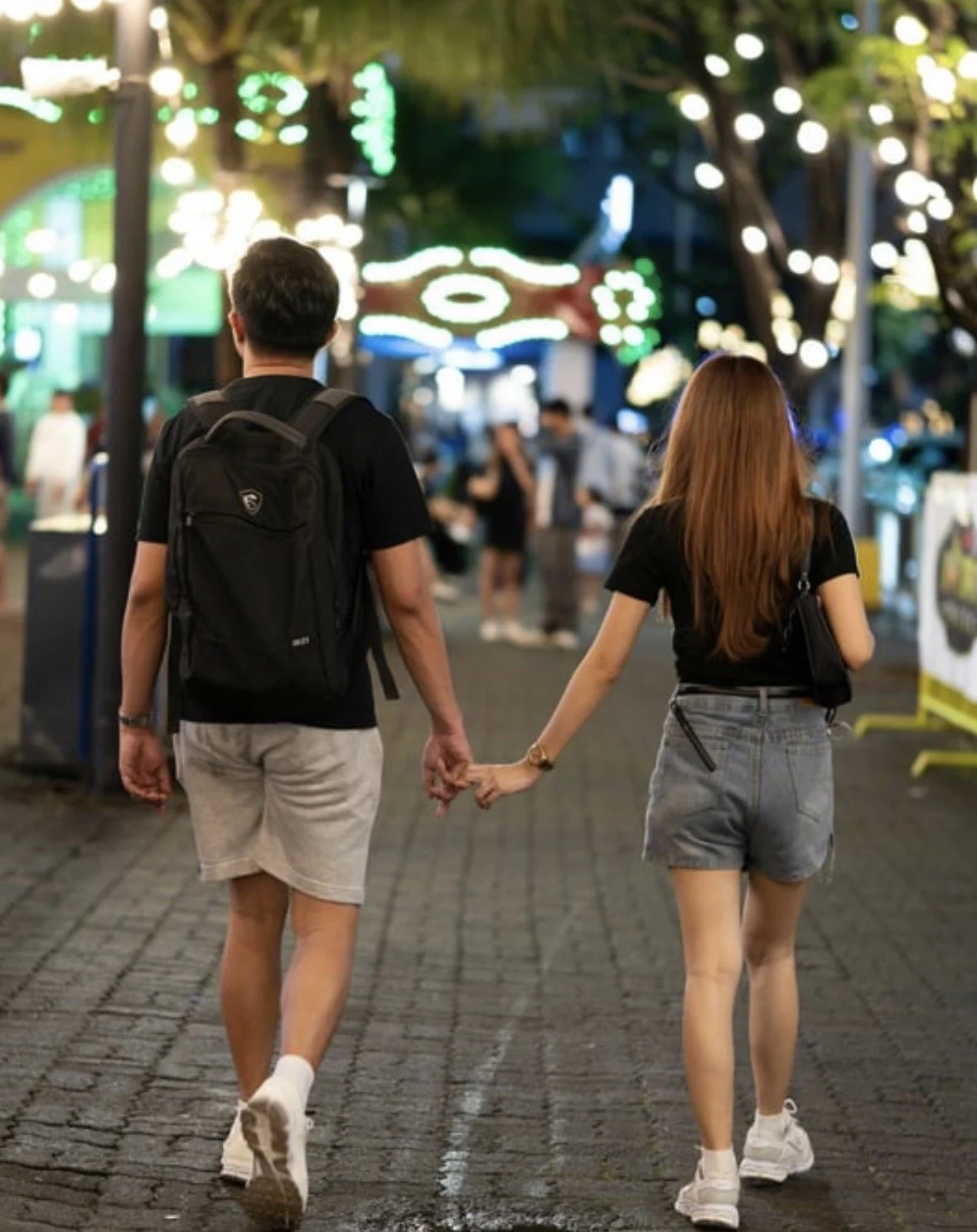 Two people walking through a lively Charlotte neighborhood in the evening after work, representing relief from heavy legs and lower-body stiffness.