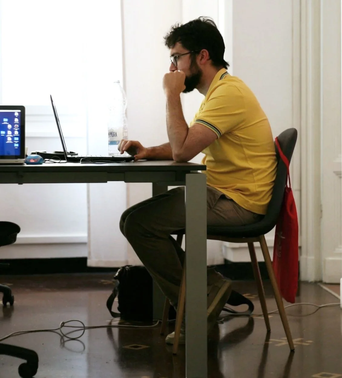 Desk worker sitting with forward posture at a computer, illustrating how prolonged sitting can contribute to hip flexor tightness, glute underactivity, and low back tension.