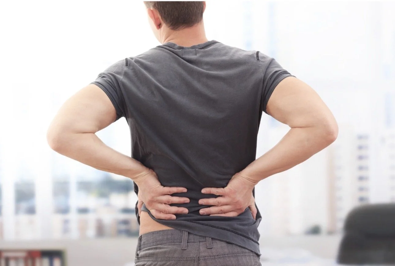 man holding low back showing discomfort from prolonged sitting and hip muscle tightness