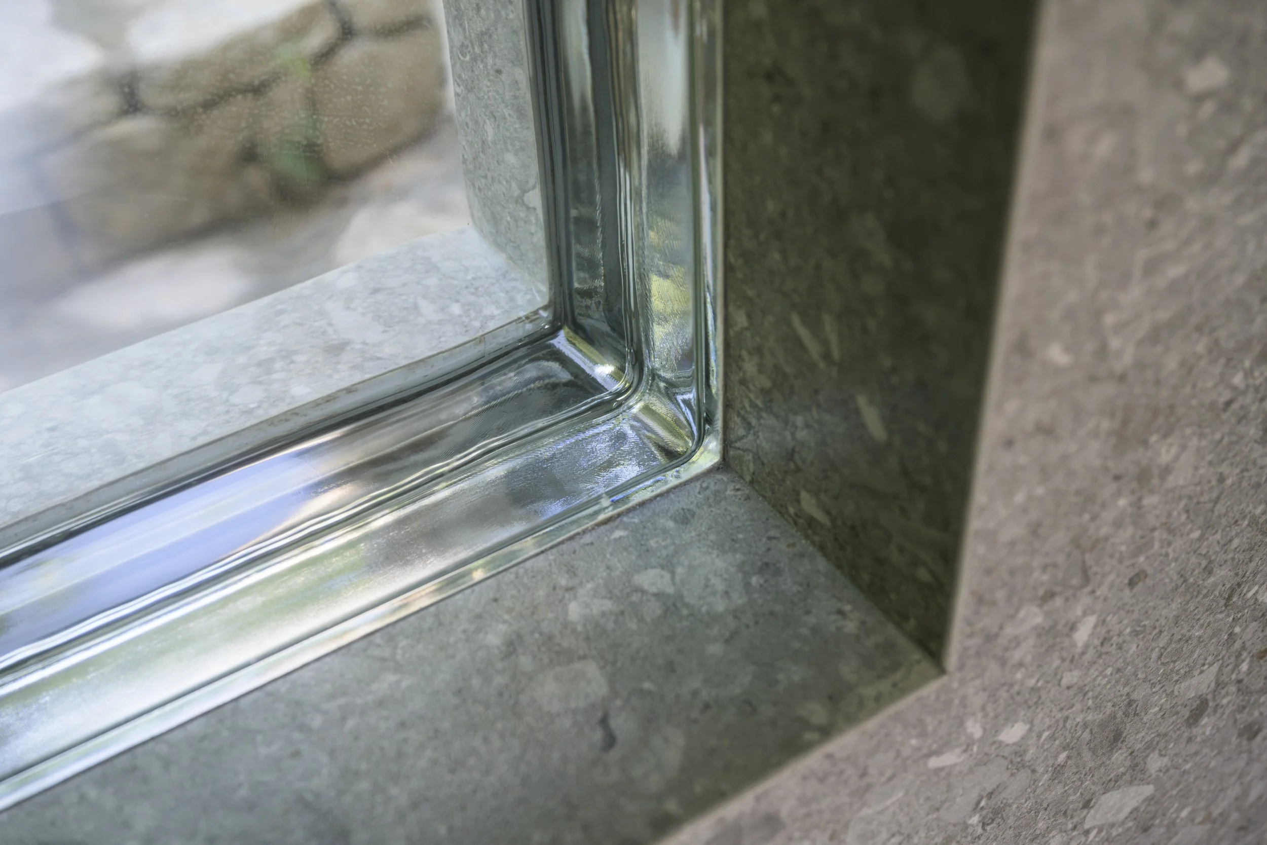 Détail intérieur : le revêtement de façade se poursuit à l'intérieur et se retourne dans l'ébrasement, autour de la brique de verre. 
