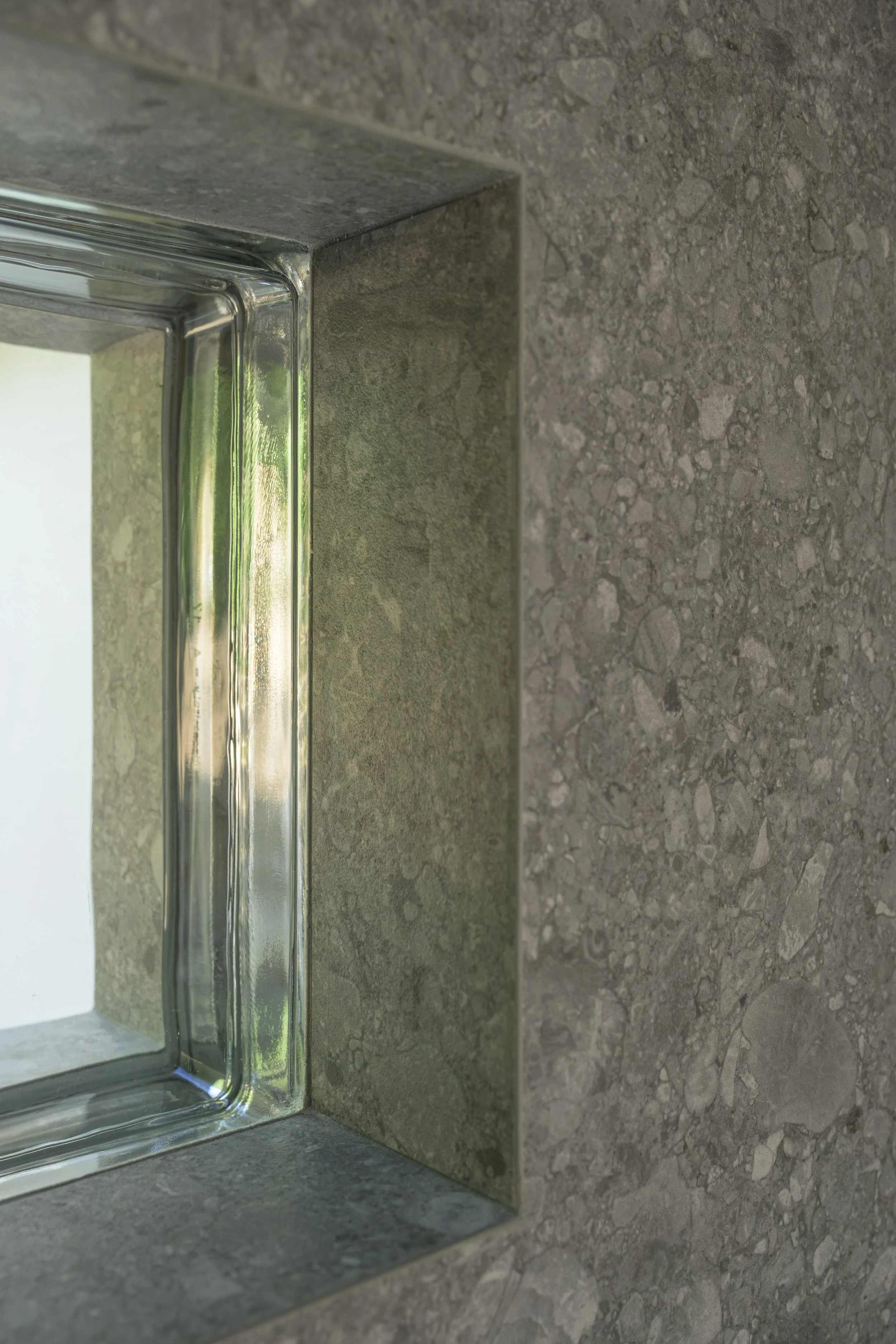 Détail intérieur : le revêtement de façade se poursuit à l'intérieur et se retourne dans l'ébrasement, autour de la brique de verre. 