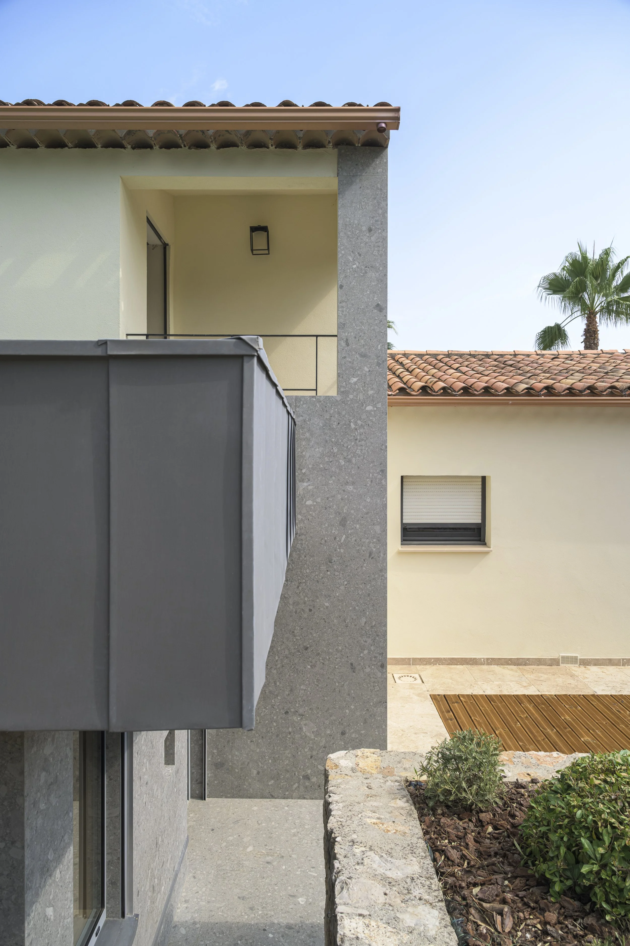 Vue depuis l'extension : le mur de la villa est habillé du même carrelage que le nouveau volume, pour lier visuellement l'existant et l'extension.