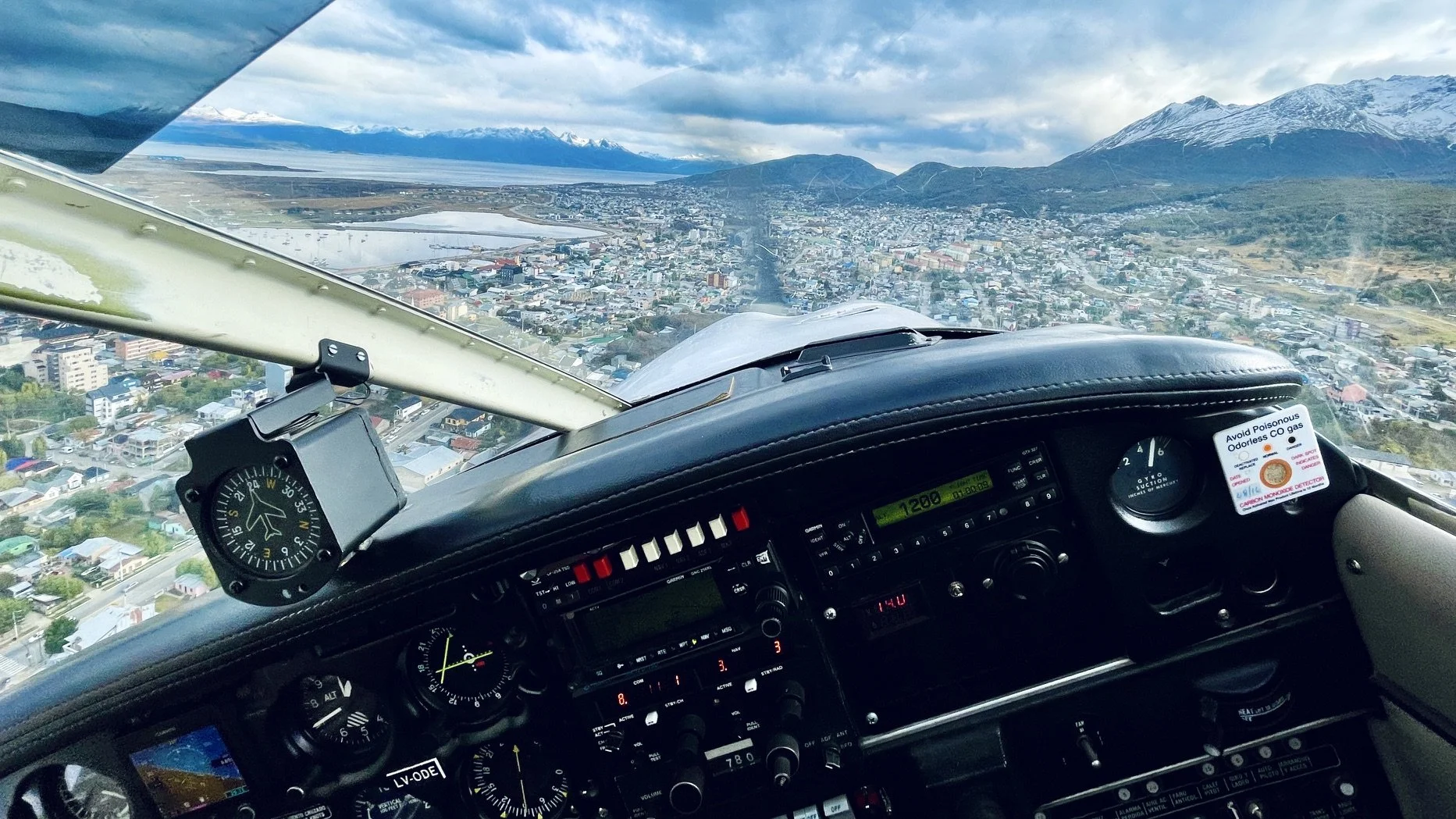 Small plane landing in Ushuaia with mountains on the background and city underneath