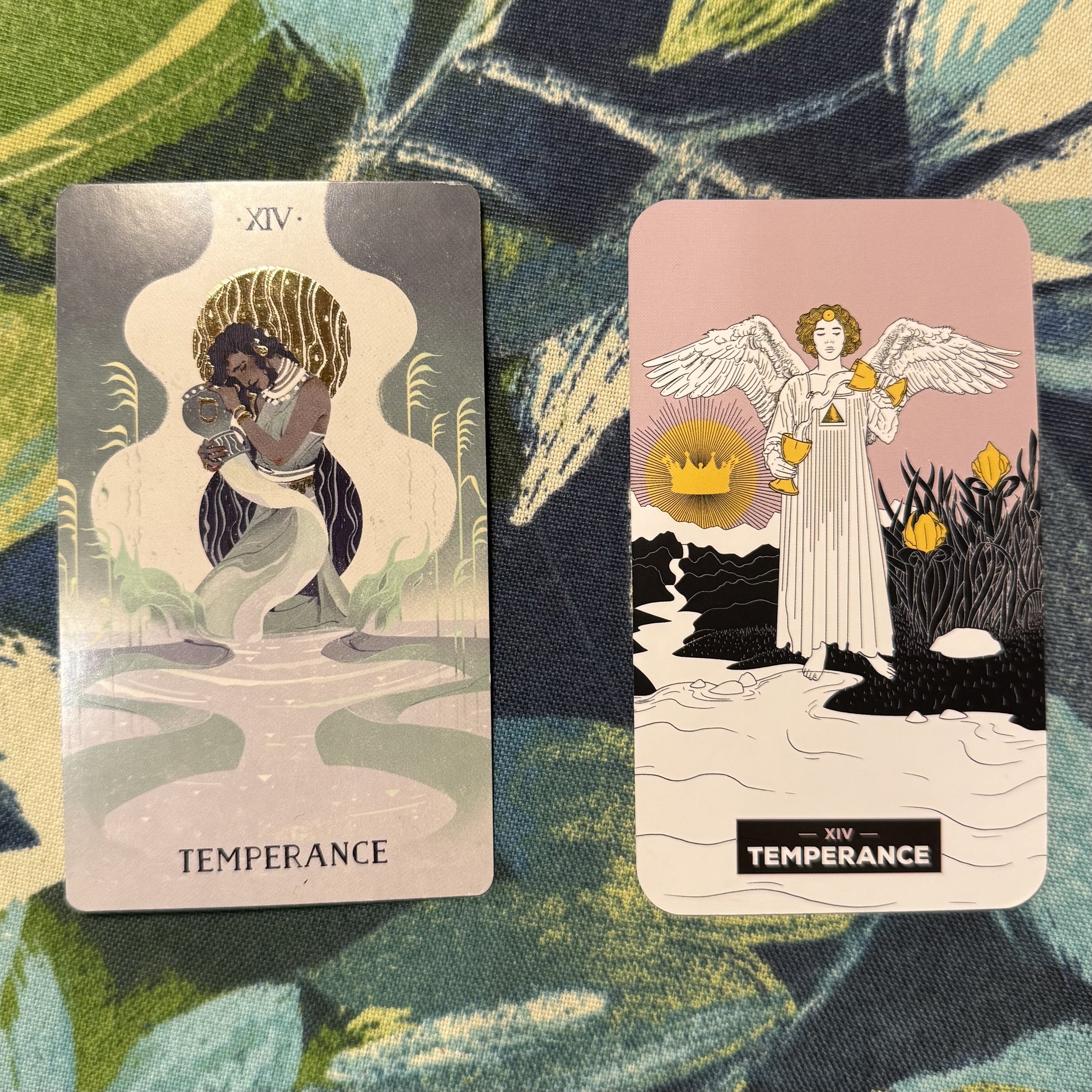 Two "Temperance" tarot cards on a patterned blue-green surface; one card features a figure embracing a jug with a gold halo, while the other depicts an angel pouring liquid from two chalices beneath a golden crown.