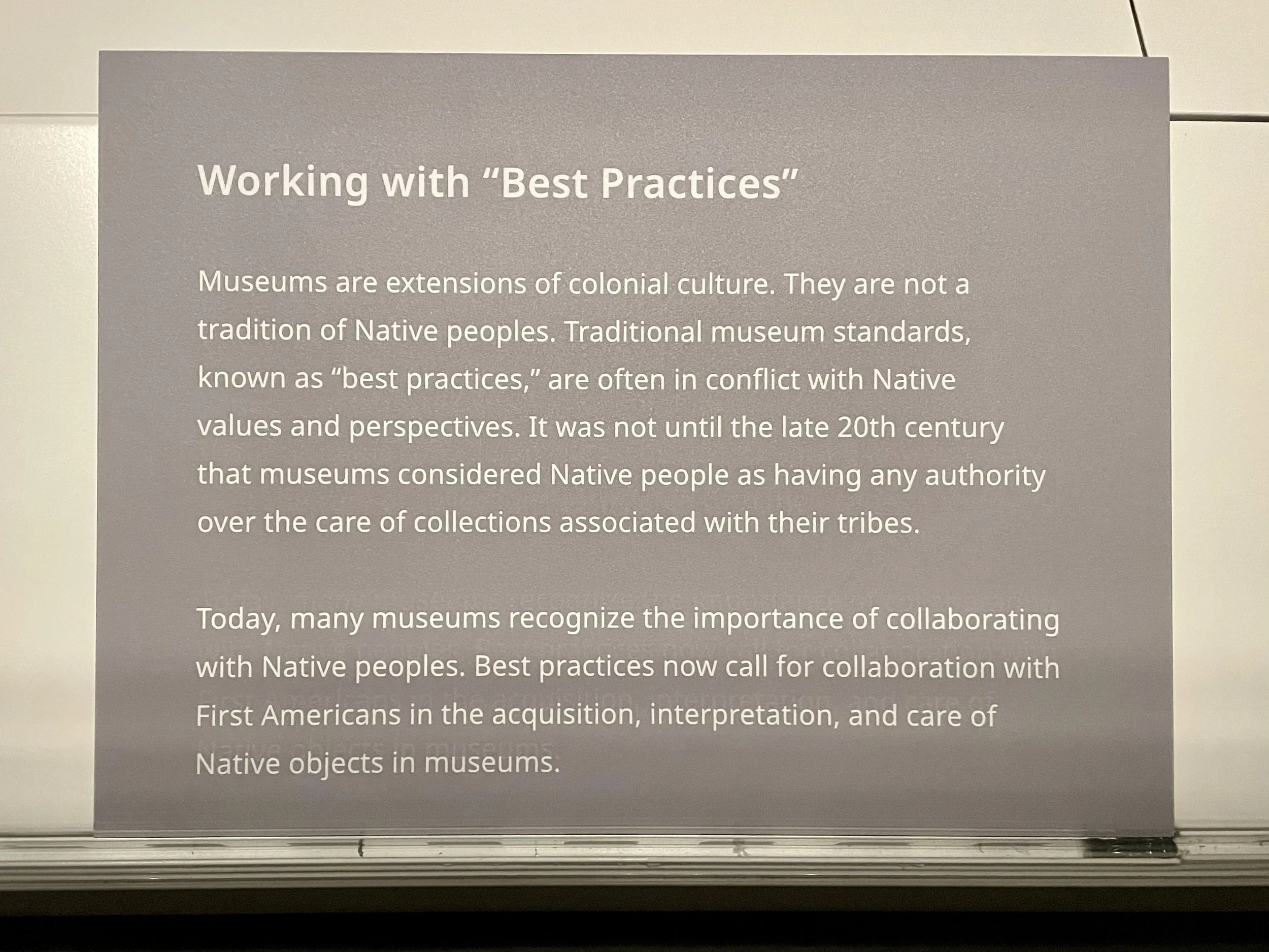 A photo of a label titled "Working with 'Best Practices'" that explains how museums are part of colonial culture and their standards of practice are often in conflict with Native values. FAM prioritizes the Native approaches.